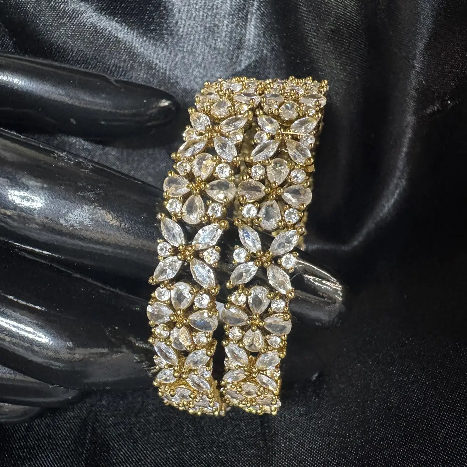 Gold-plated and crystal gemstone bangles with flower patterns on a black background