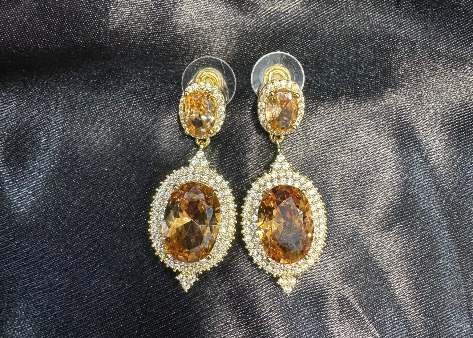Pair of gold and champagne gemstone earrings on a dark fabric background