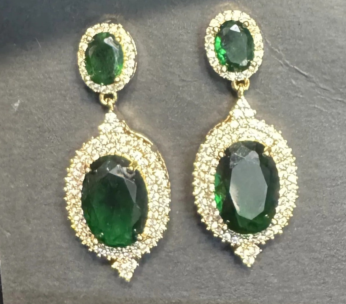 Pair of green gemstone earrings on a black card with a black satin background