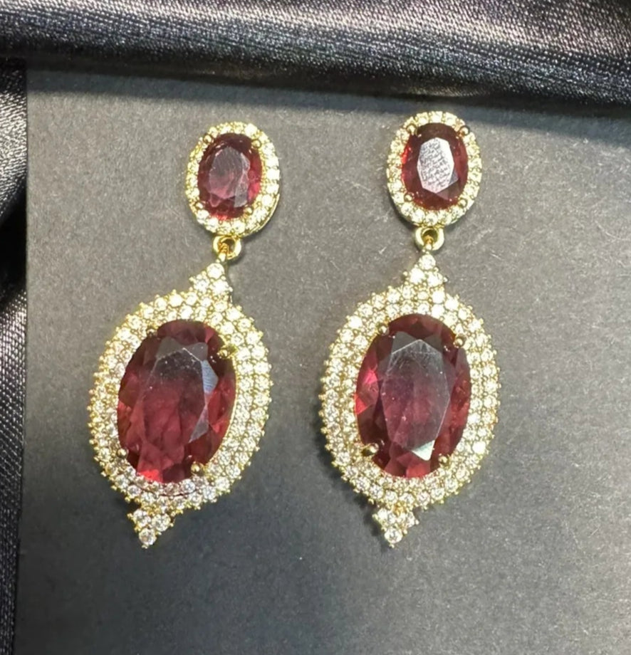 Pair of red gemstone earrings on a black card against a black satin background