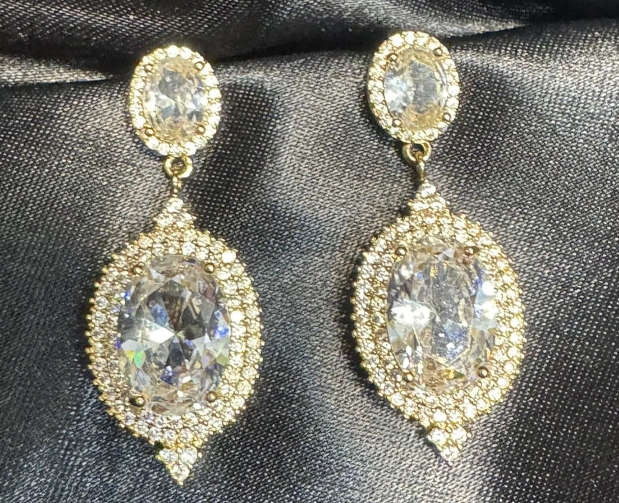 Pair of gold and crystal clear earrings on black satin fabric