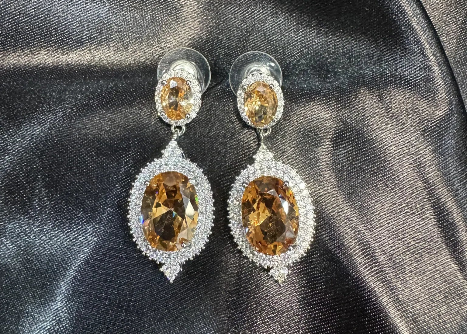 Pair of earrings with champagne gemstones on a dark fabric background