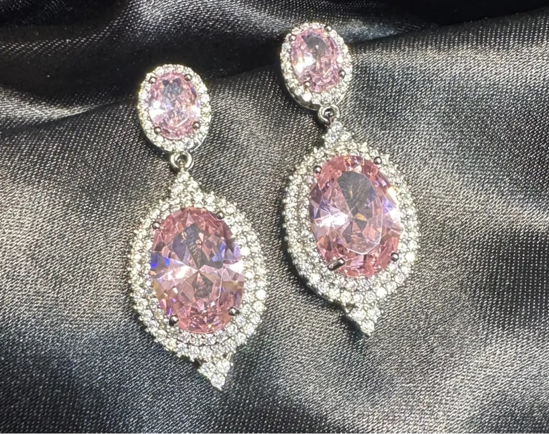 Pink gemstone earrings on a black satin background