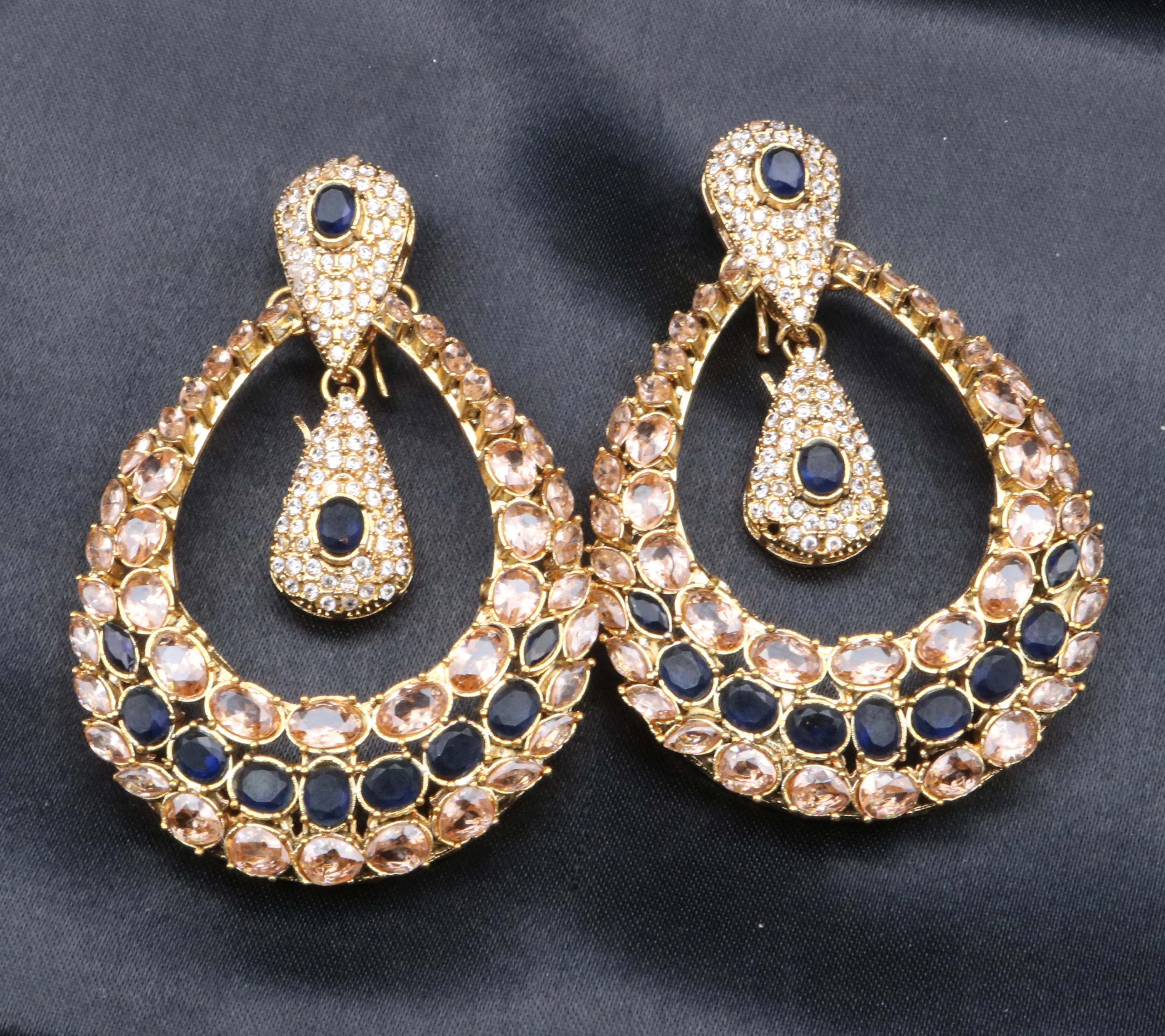 Handcrafted in Pakistan Gold and blue earrings on a black satin background. They are gold-plated and waterproof