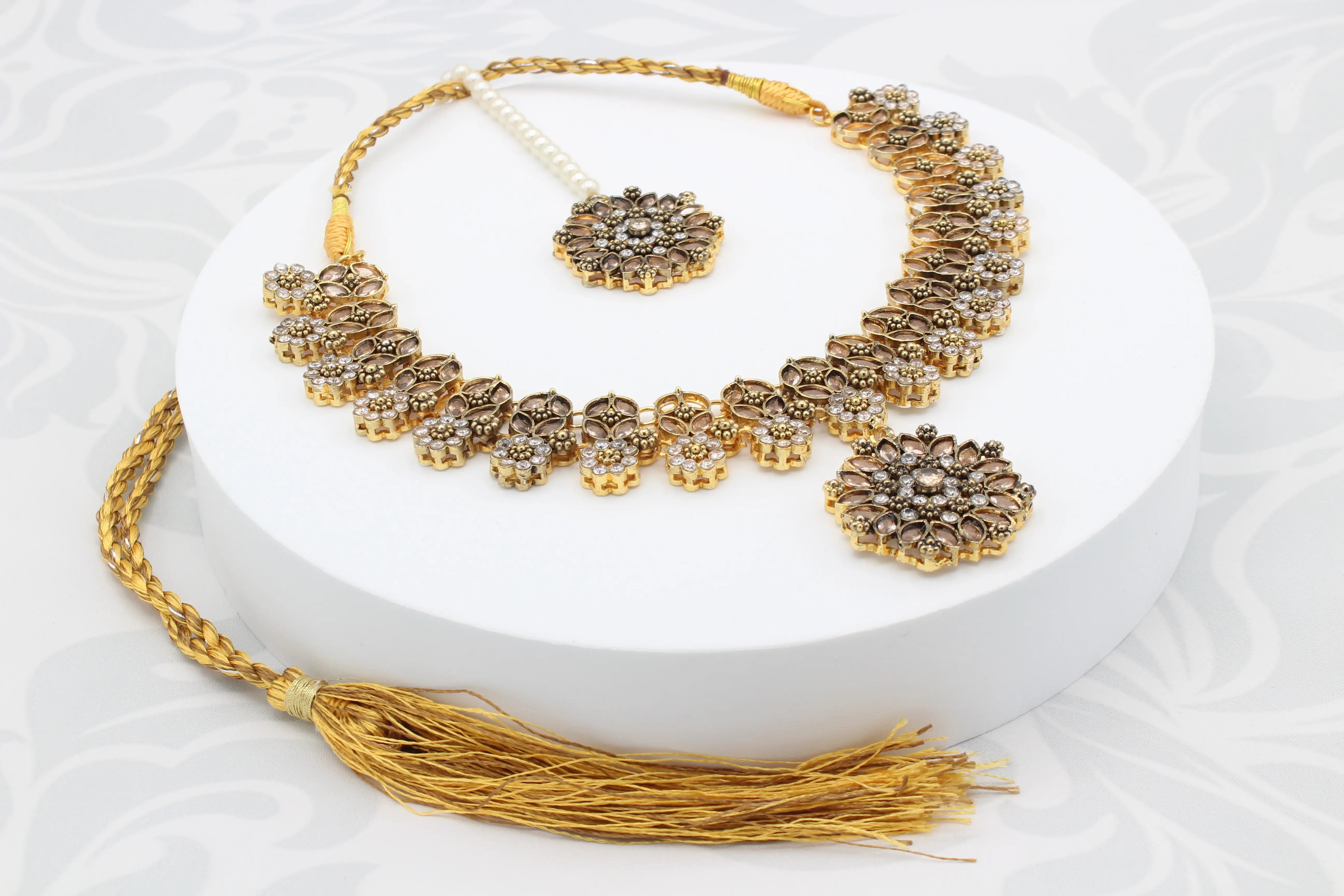 Angled display of necklace with detachable pendant and golden dori on round white stand