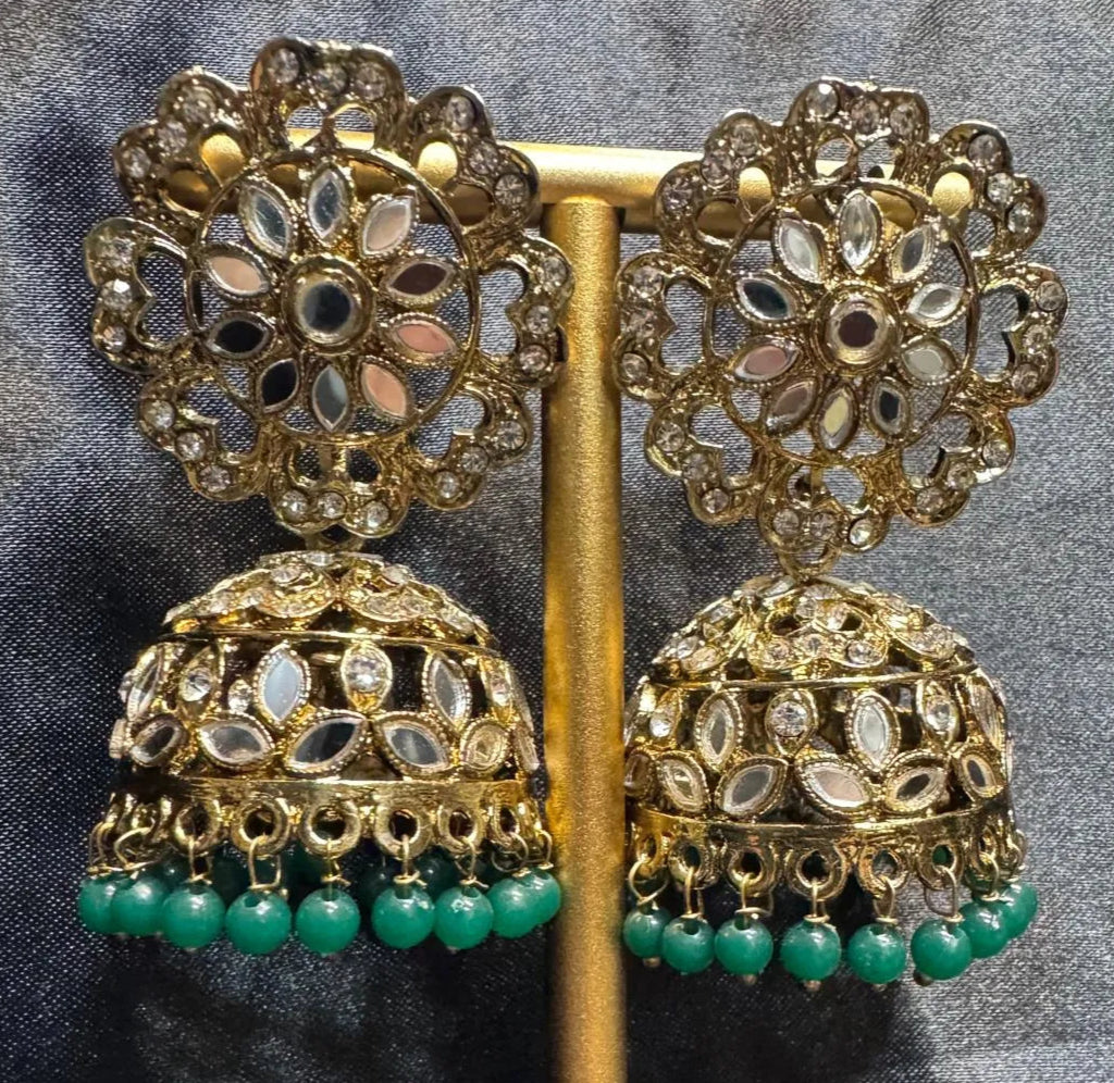 Ornate gold plated and green earrings on a gray background