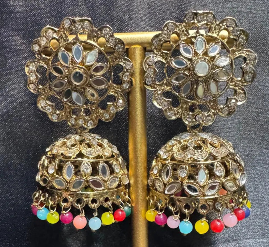Ornate gold plated earrings/jhumka with multi color beads on a dark fabric background