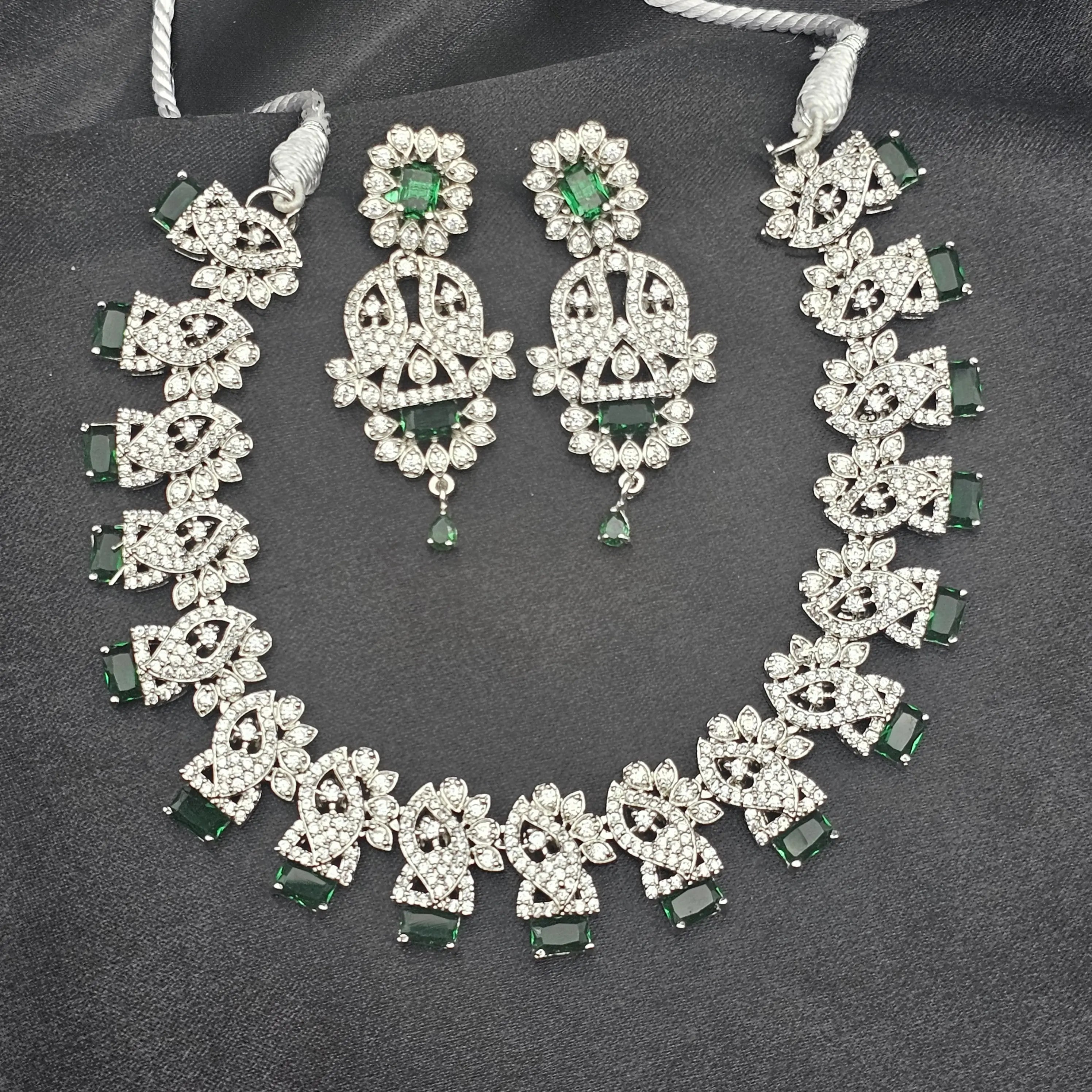 Full Felicity silver-toned necklace set with emerald green rectangular stones and matching earrings displayed on black fabric.