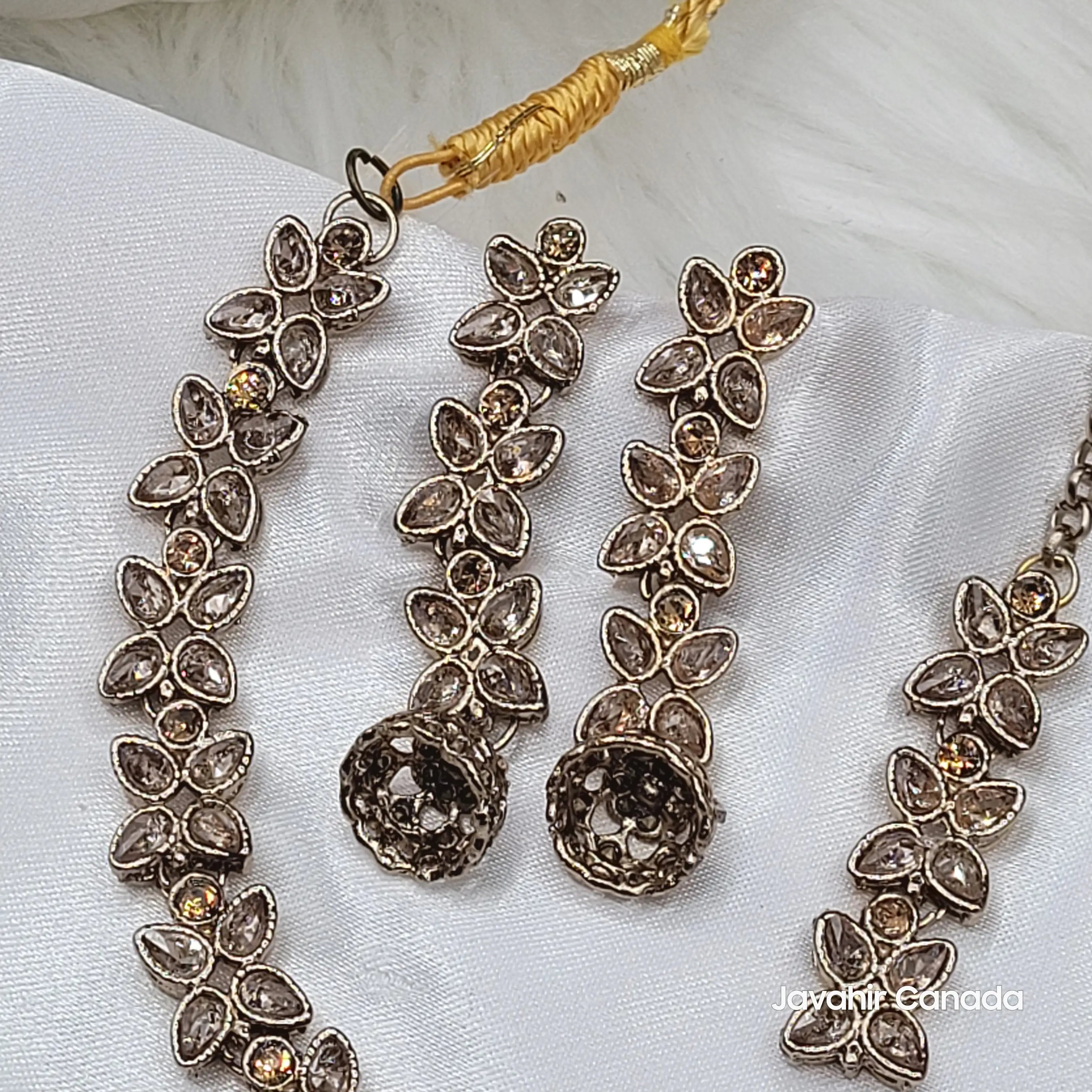 Angled top view of Flora champagne necklace and earrings set laid out flat on satin.