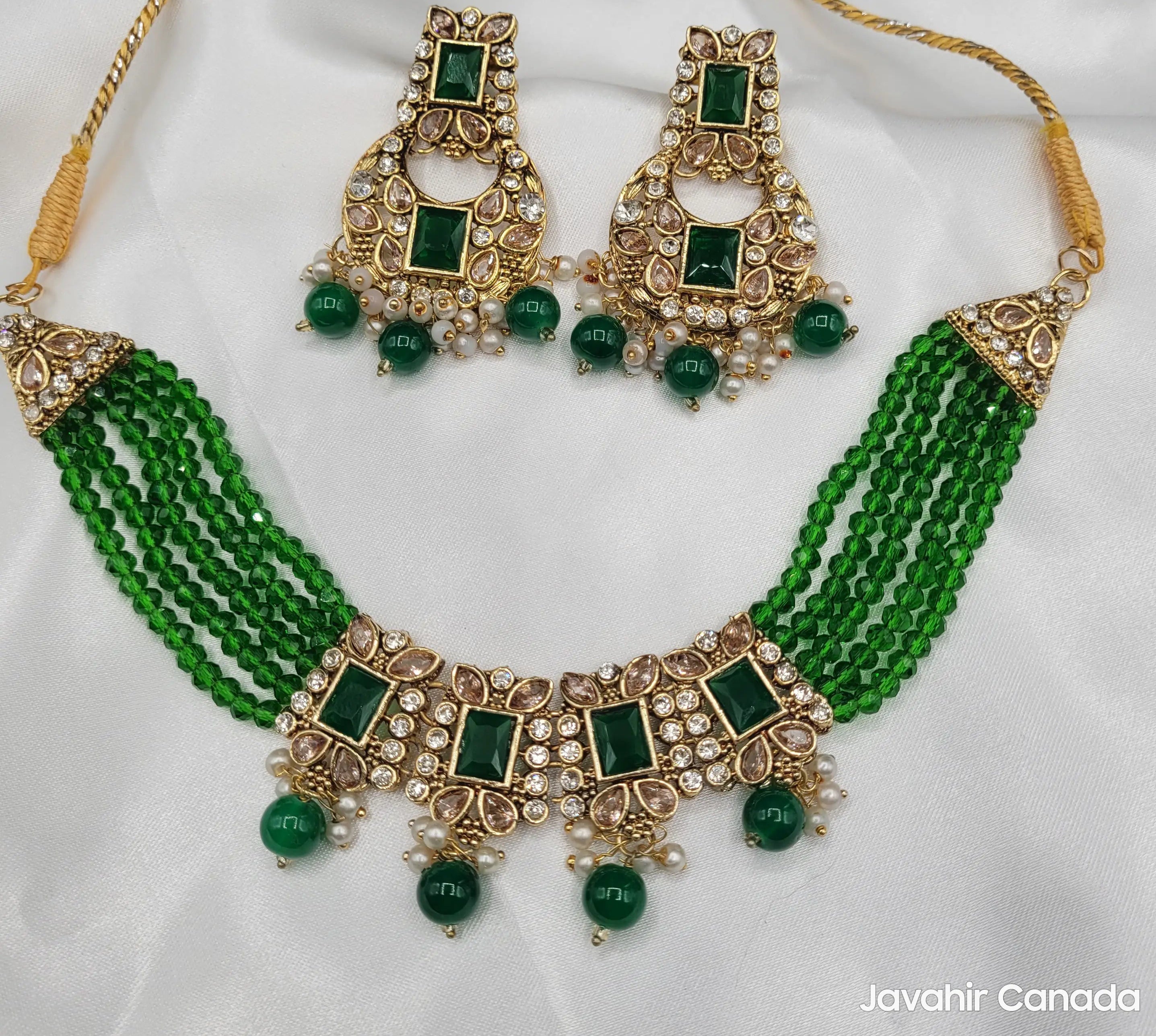 Firdous emerald green beaded necklace set with earrings on white fabric display.