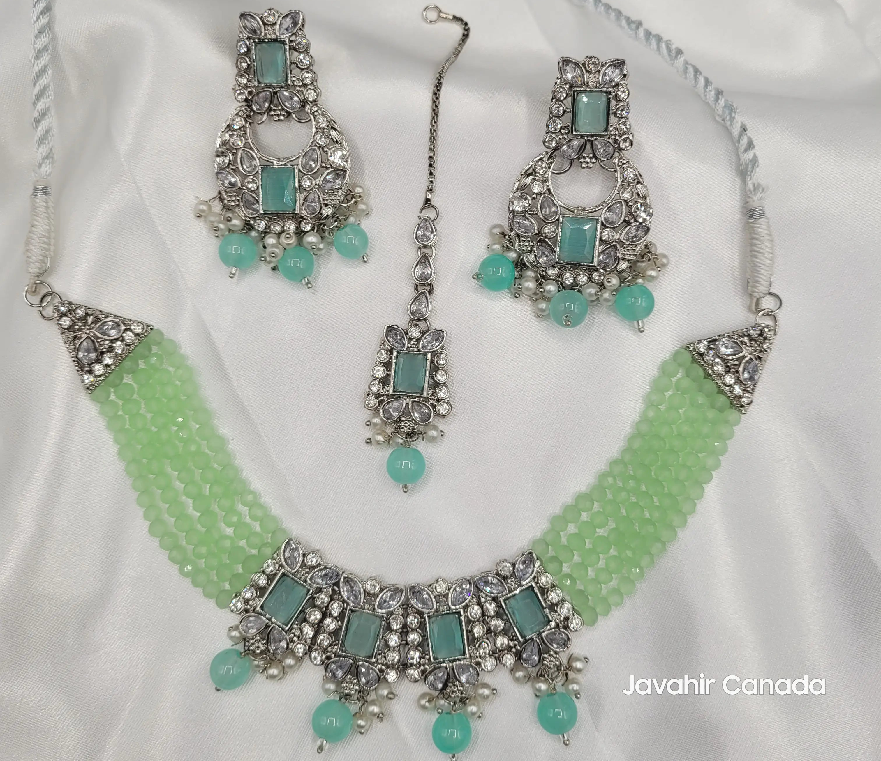 Full Firdous mint green set with necklace, earrings, and maang tikka displayed on white fabric.