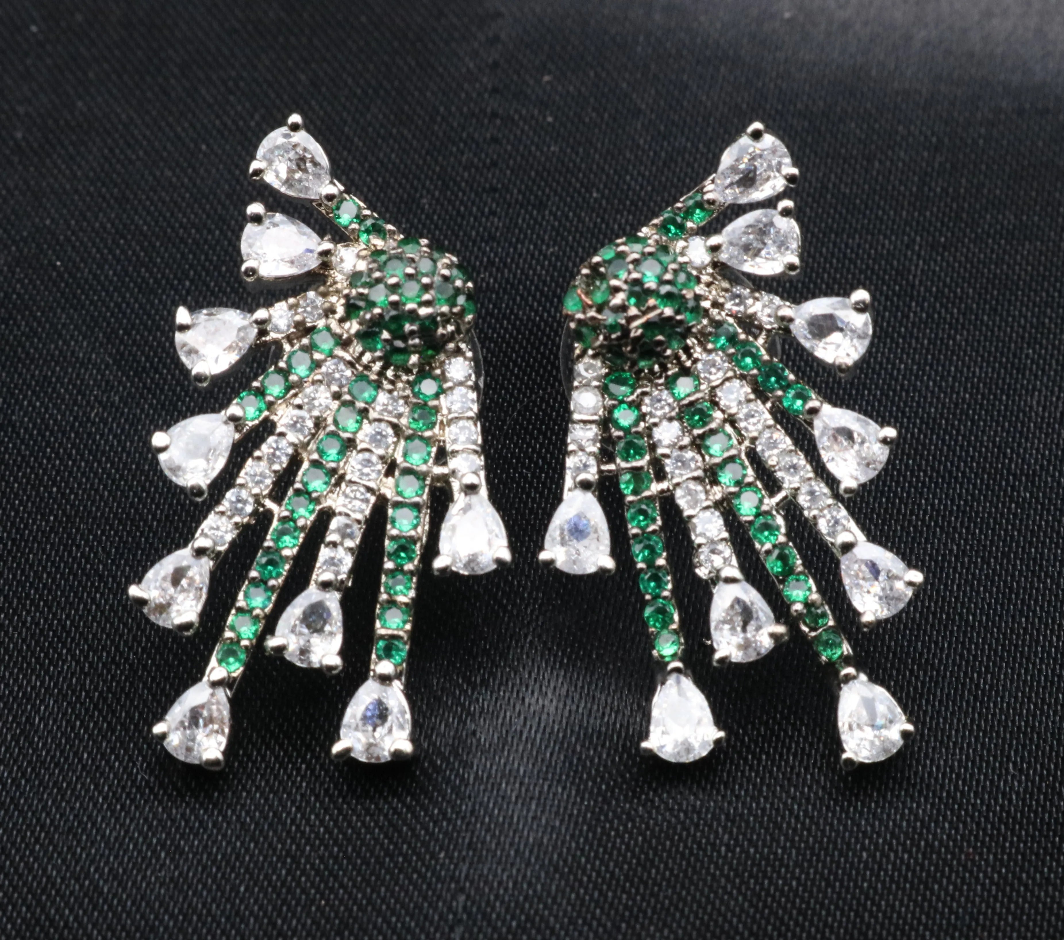 Pair of green and silver earrings on a black background