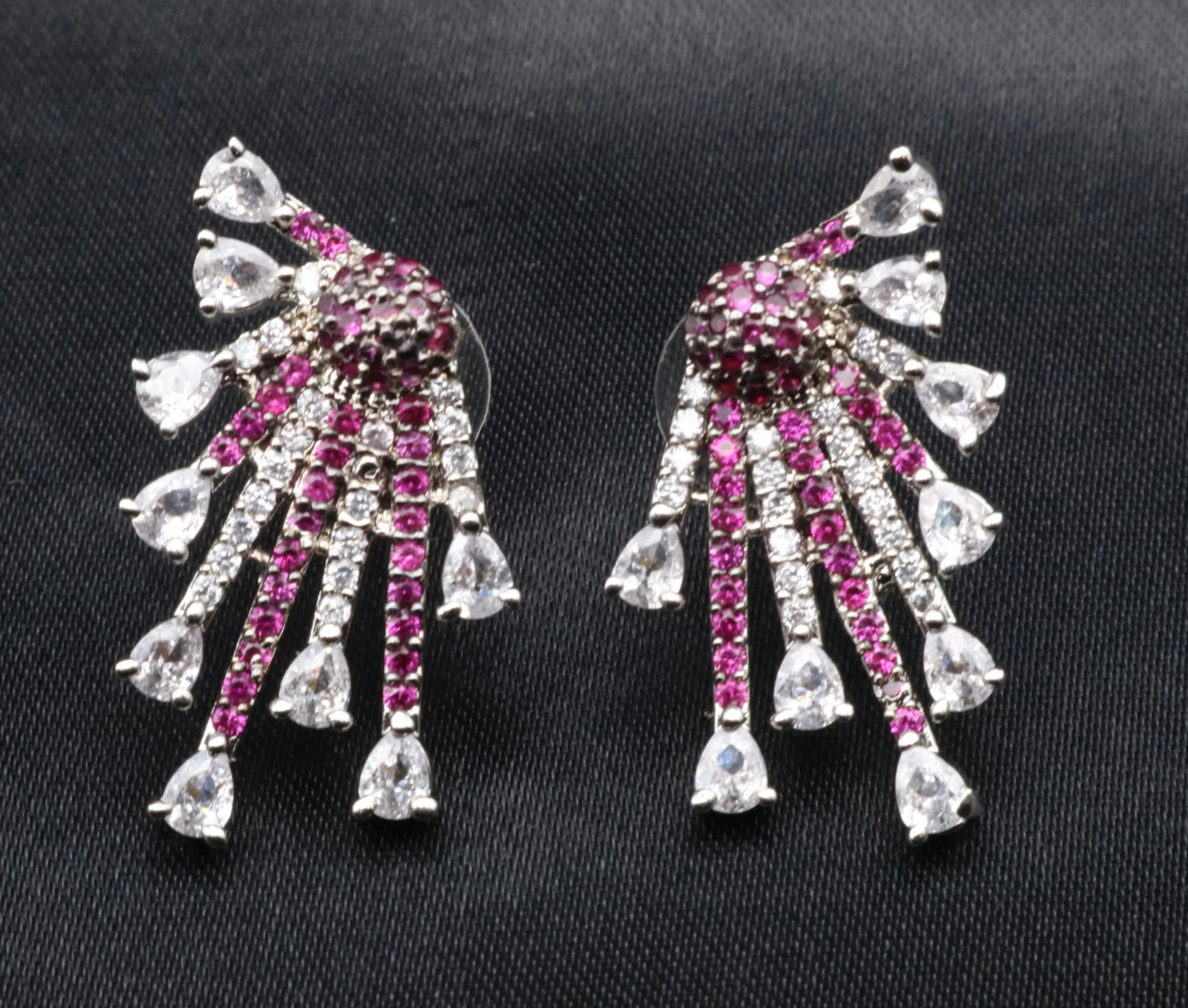 Pair of earrings with pink and clear gemstones on a black background