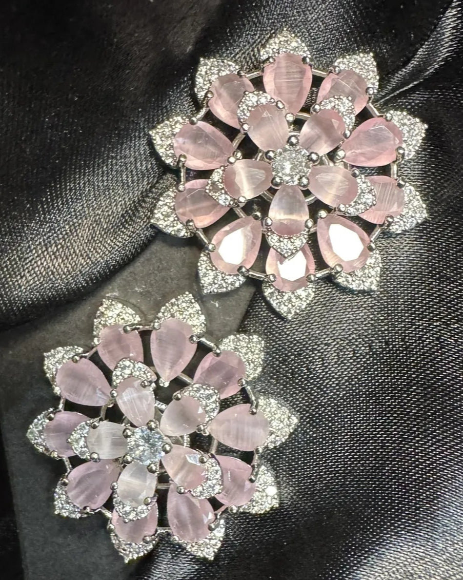 Pair of pink floral earrings on a black satin background