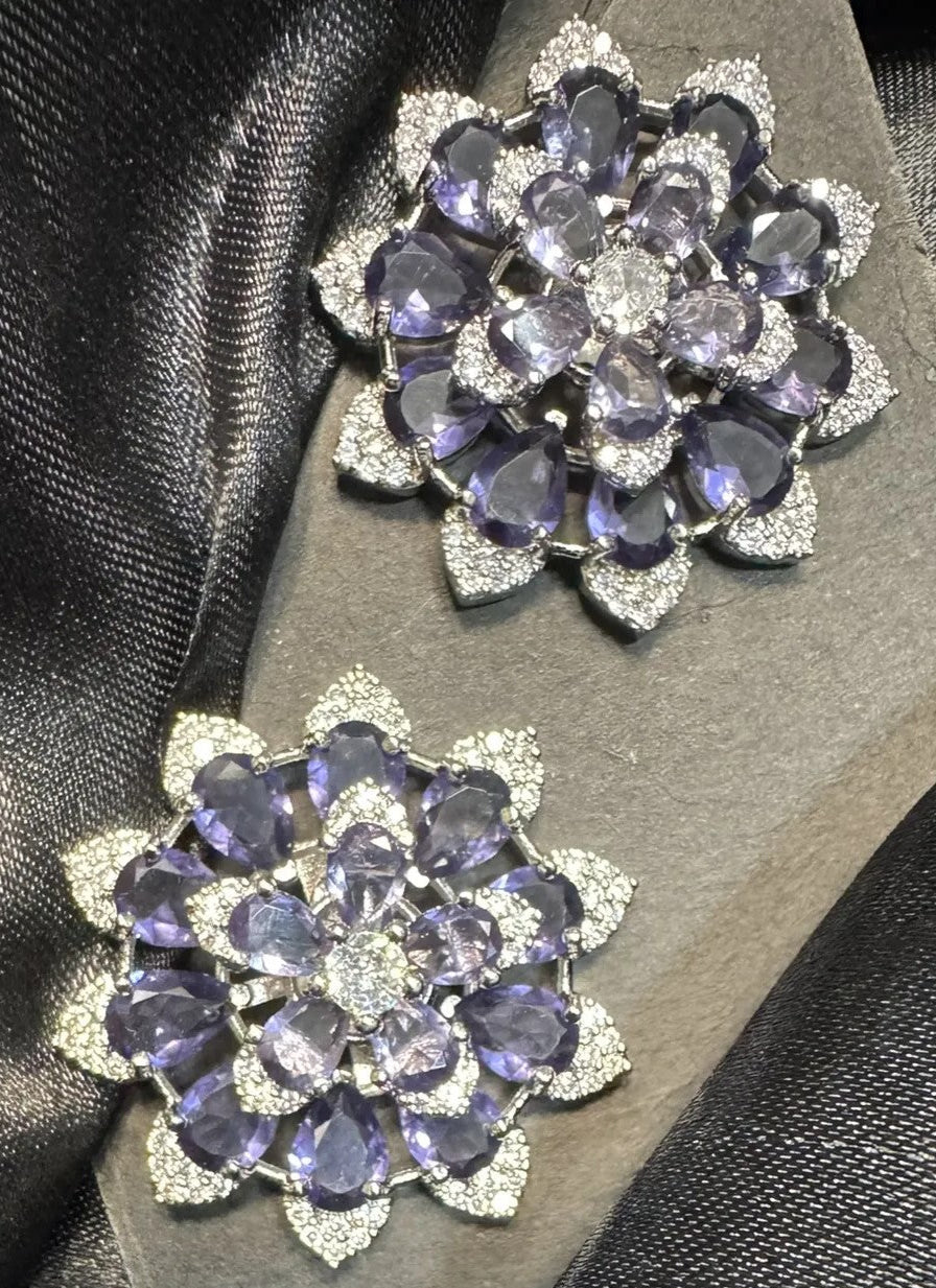 Pair of purple floral earrings on a dark fabric background