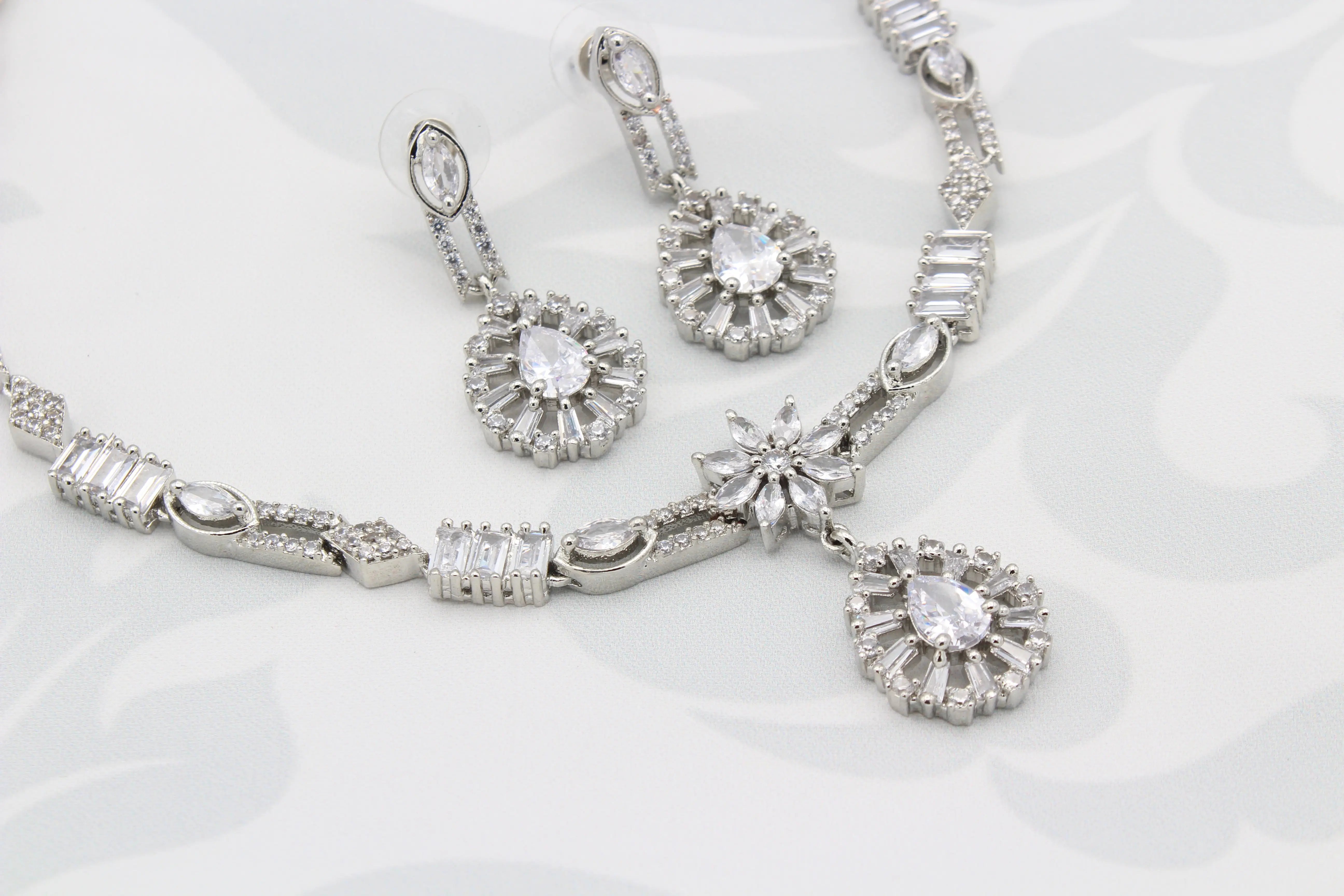 Close-up of Frosted White AD Vine Necklace Set with floral center and teardrop earrings