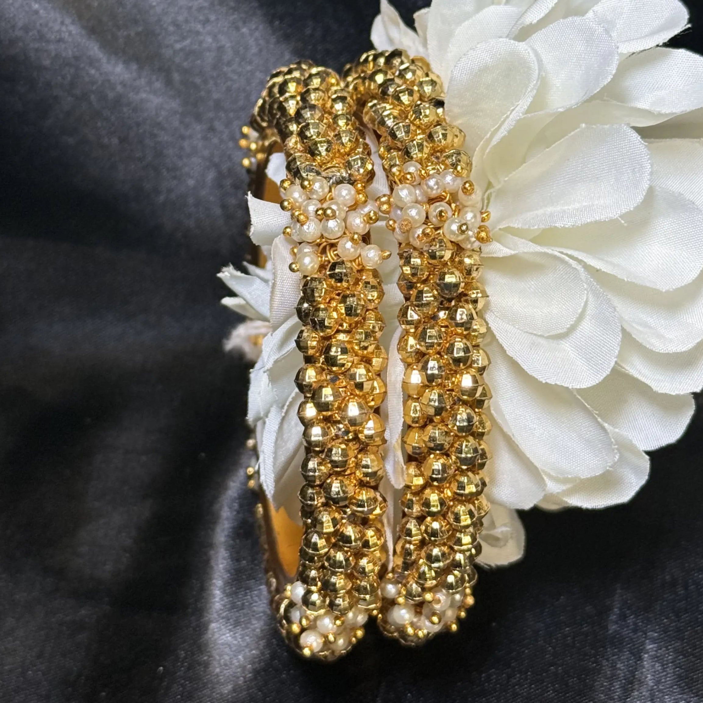 Gold festive bangles resting on white floral decor