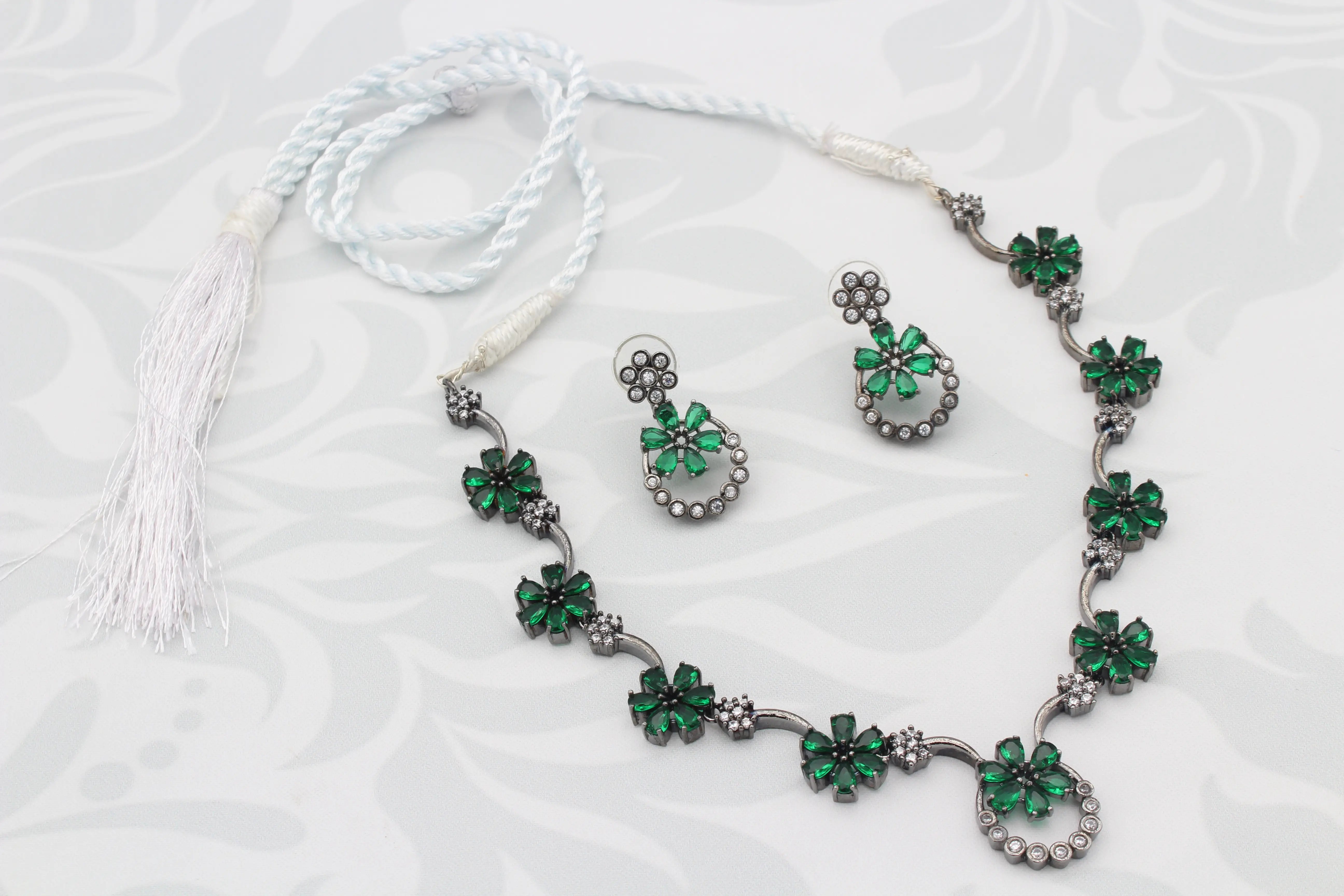 Full view of Green Floral American Diamond Necklace Set with earrings and white thread tie on display