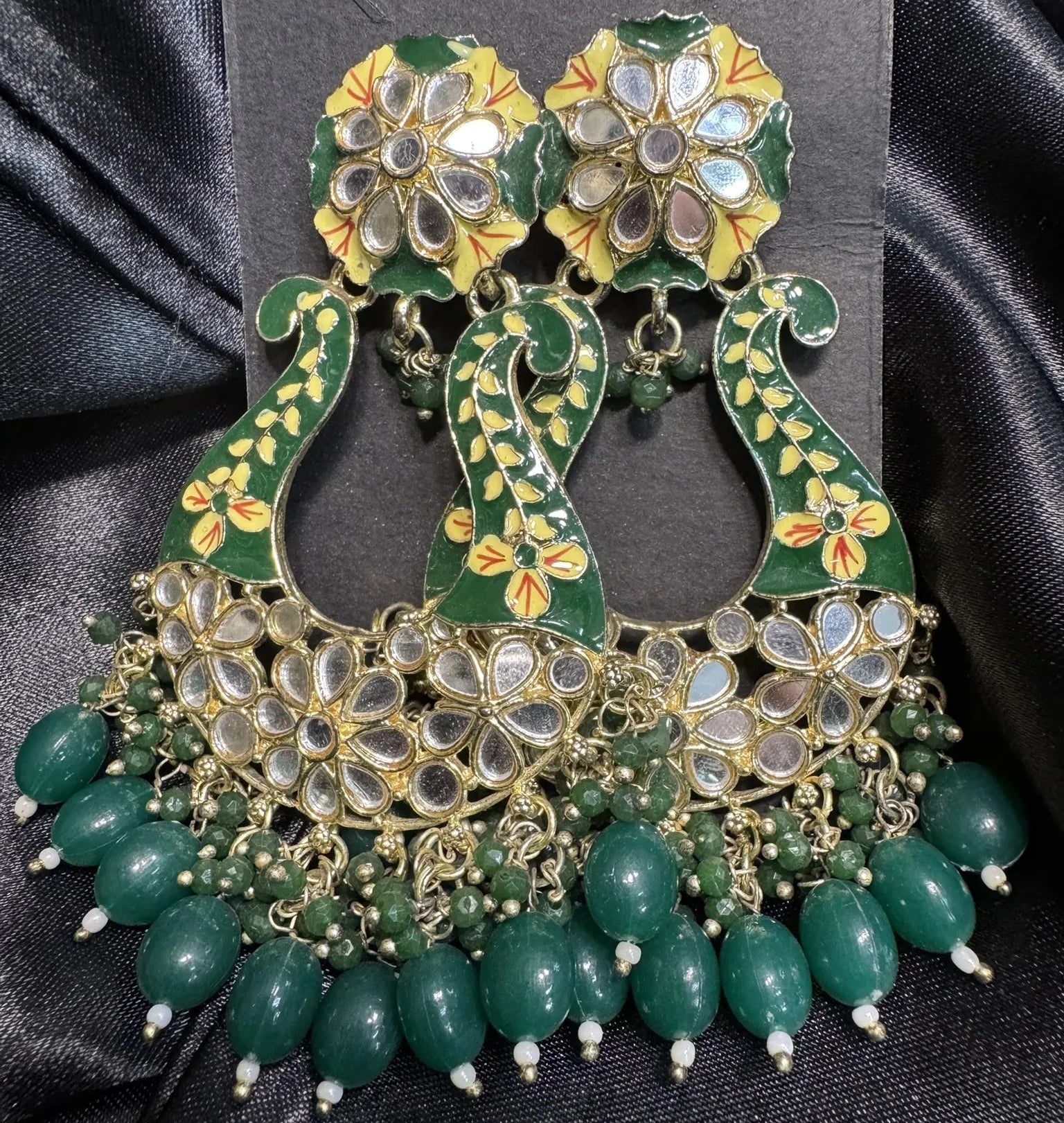 green ornate earrings with florals and black background
