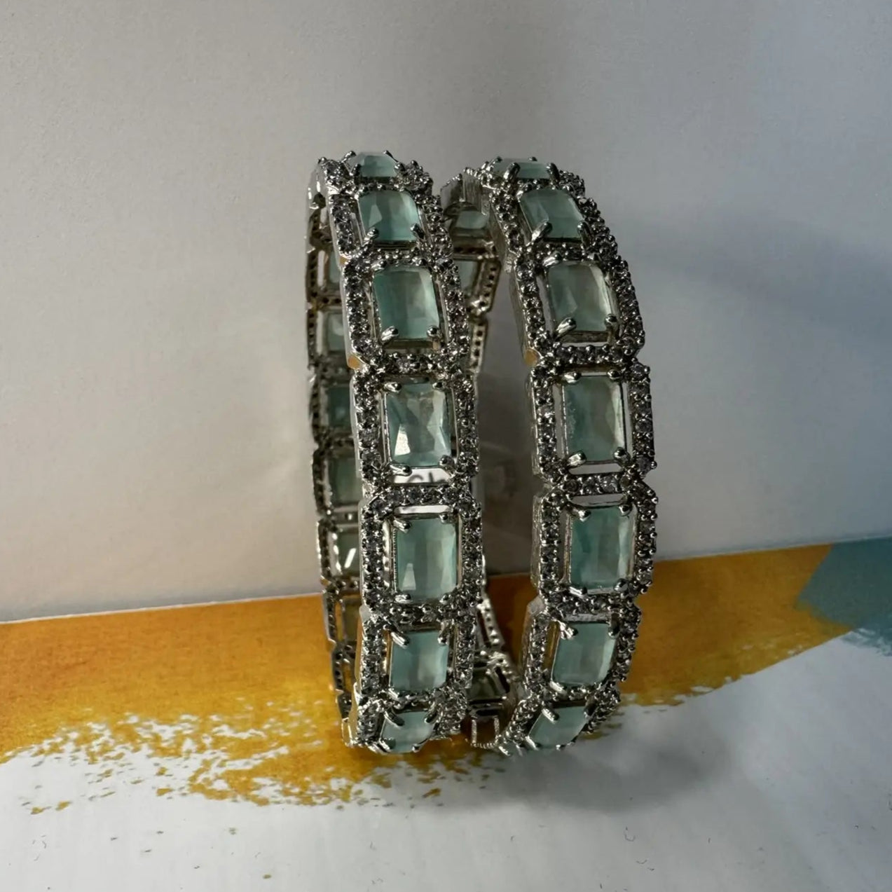 Bangles with teal gemstones and silver accents on a white surface