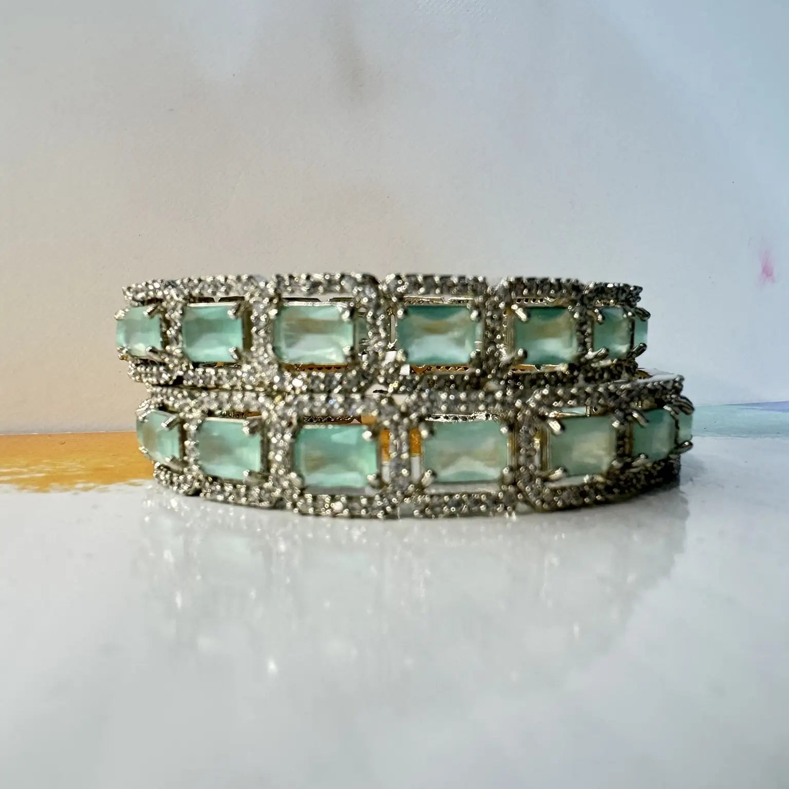 Multistrand bangles with teal gemstones on a white surface