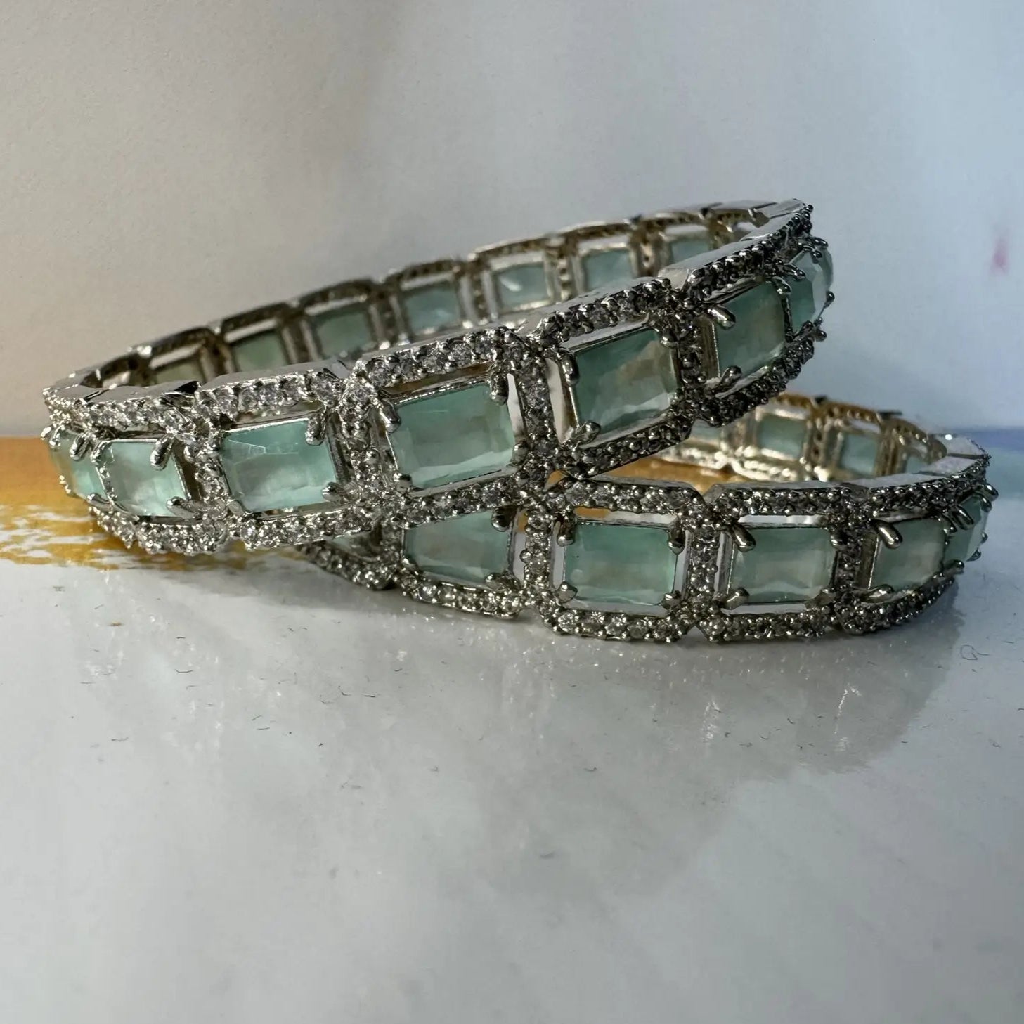 Bangles with teal gemstones and silver accents on a light background on a white surface