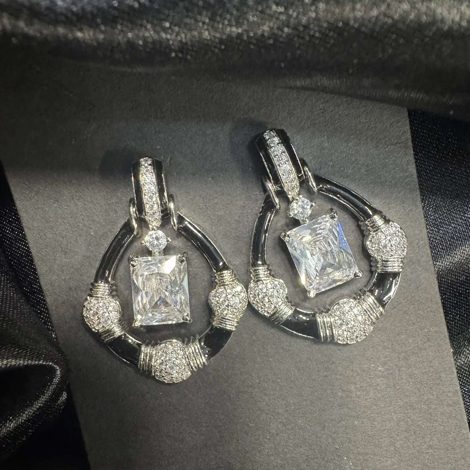Pair of diamond earrings on a black card