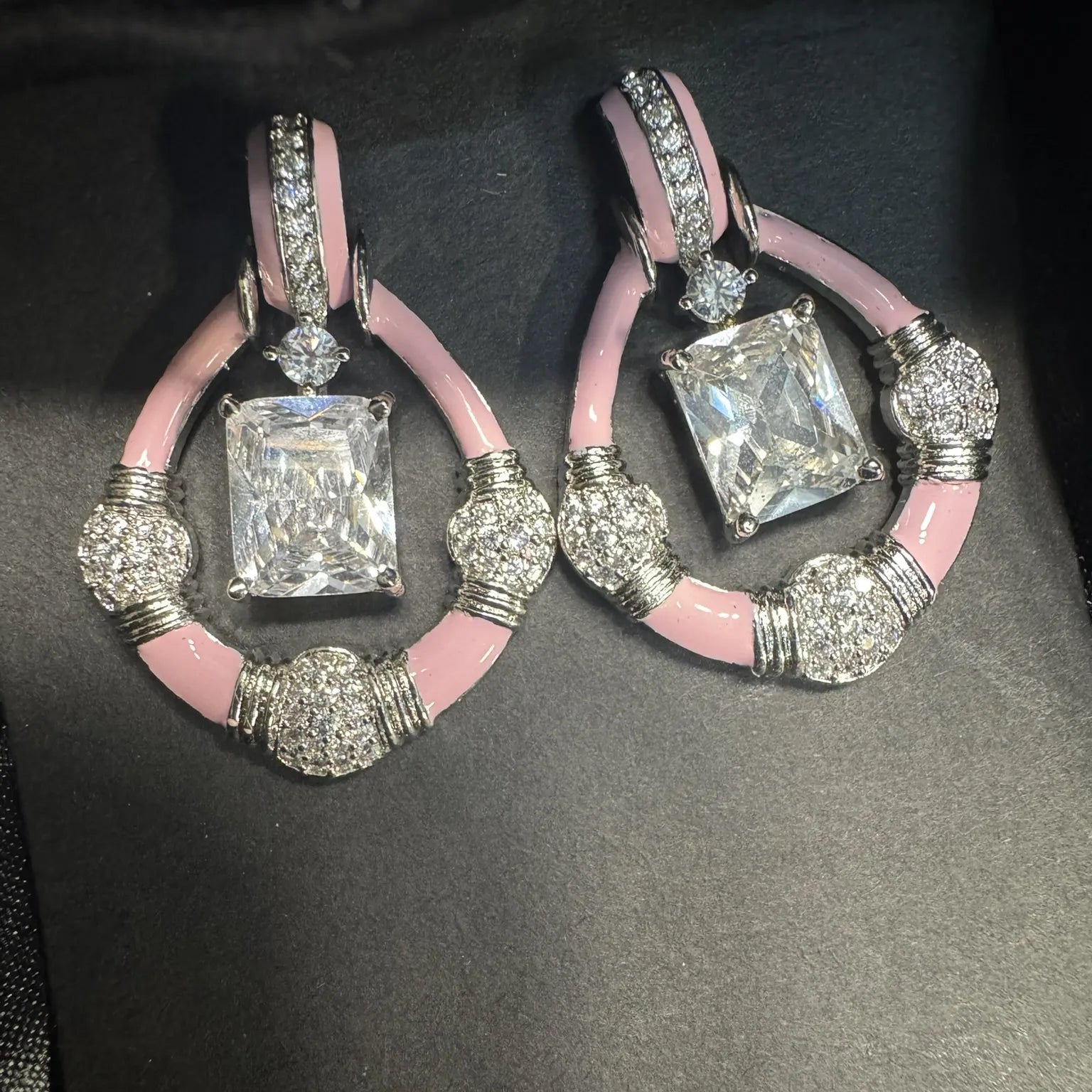 Pair of earrings with pink and silver design on a black background