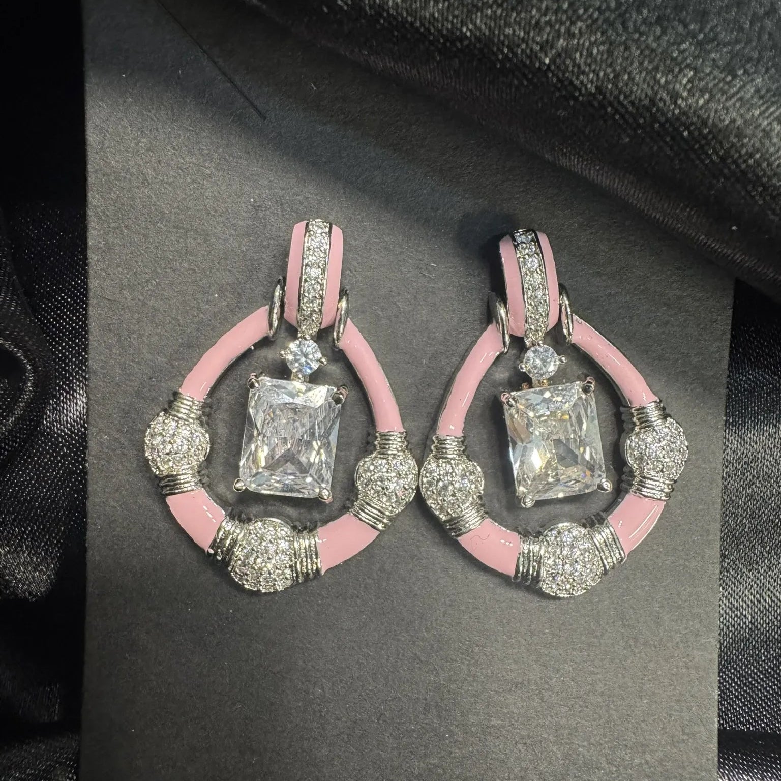 Pair of earrings with pink and silver design on a black card
