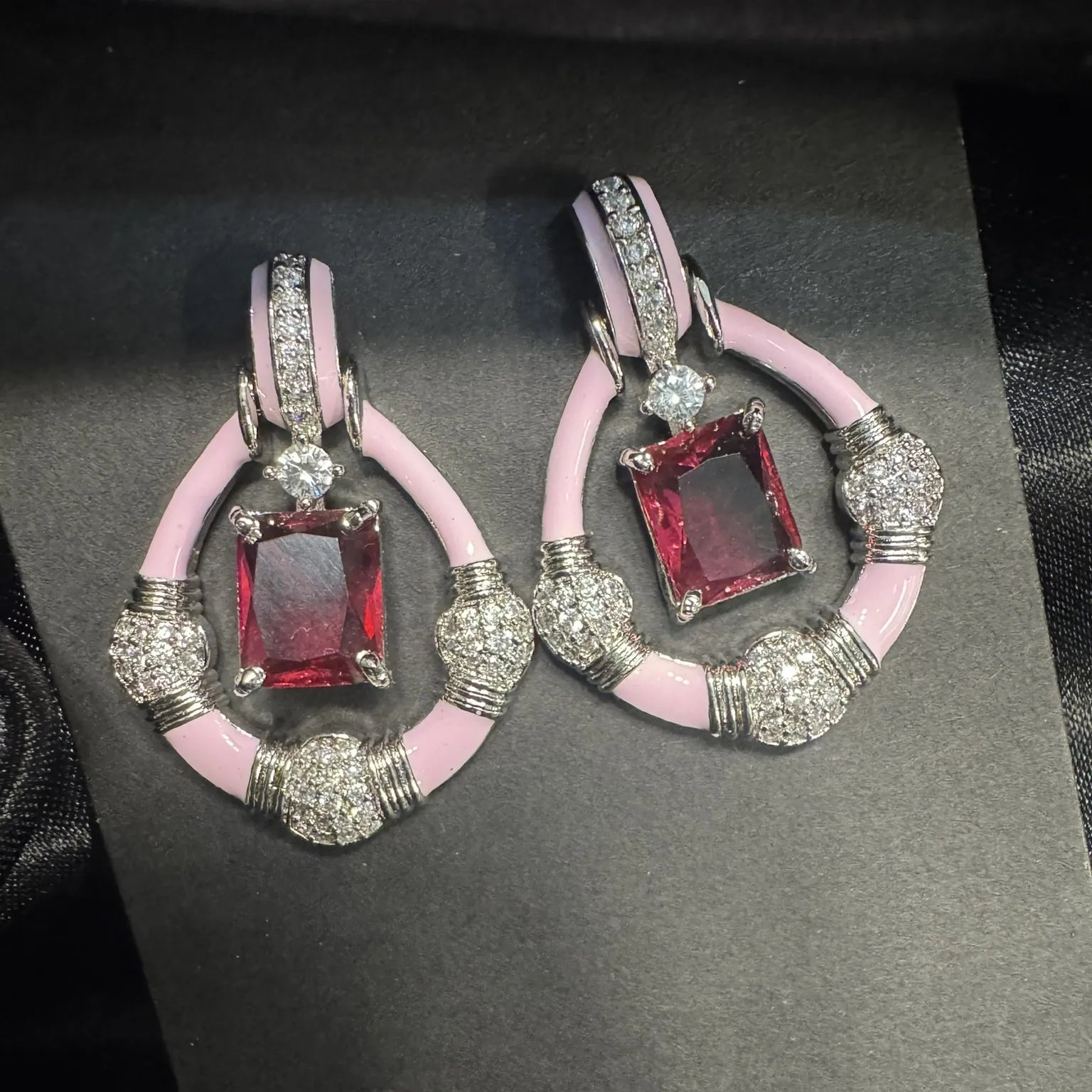 Pair of earrings with pink and hotpink gemstones on a black card