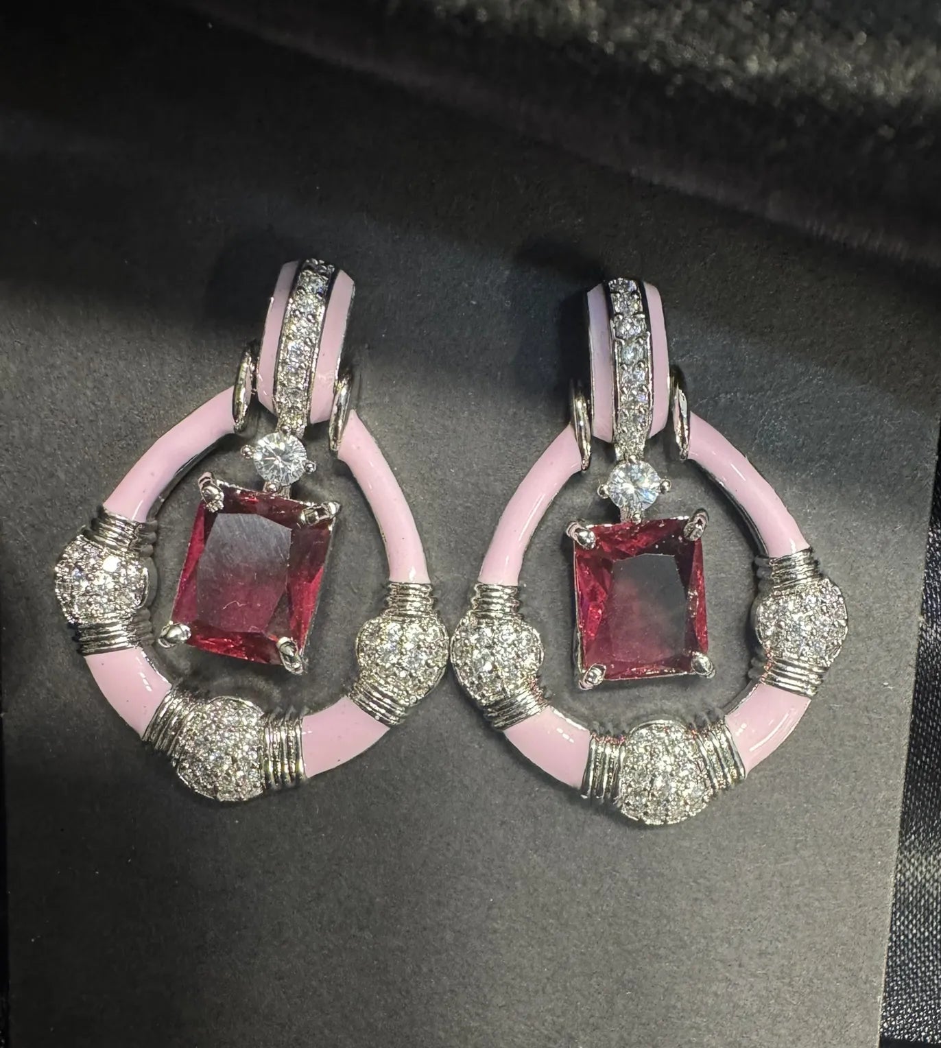 Pair of earrings with pink and hotpink gemstones on a black background