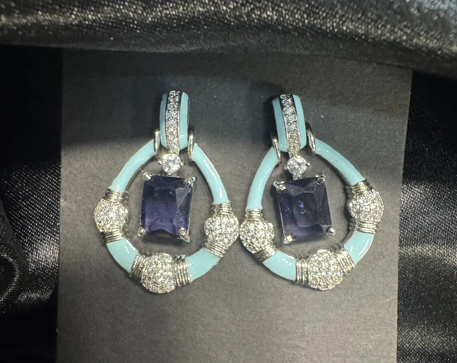 Pair of earrings with blue stones and turquoise accents on a black card.