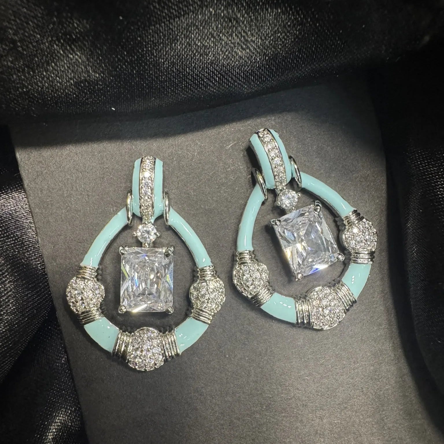 Pair of earrings with turquoise and silver design on a black background