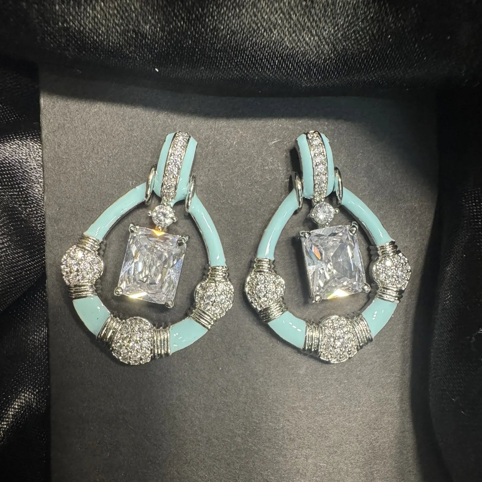 Pair of earrings with turquoise and silver design on a black background