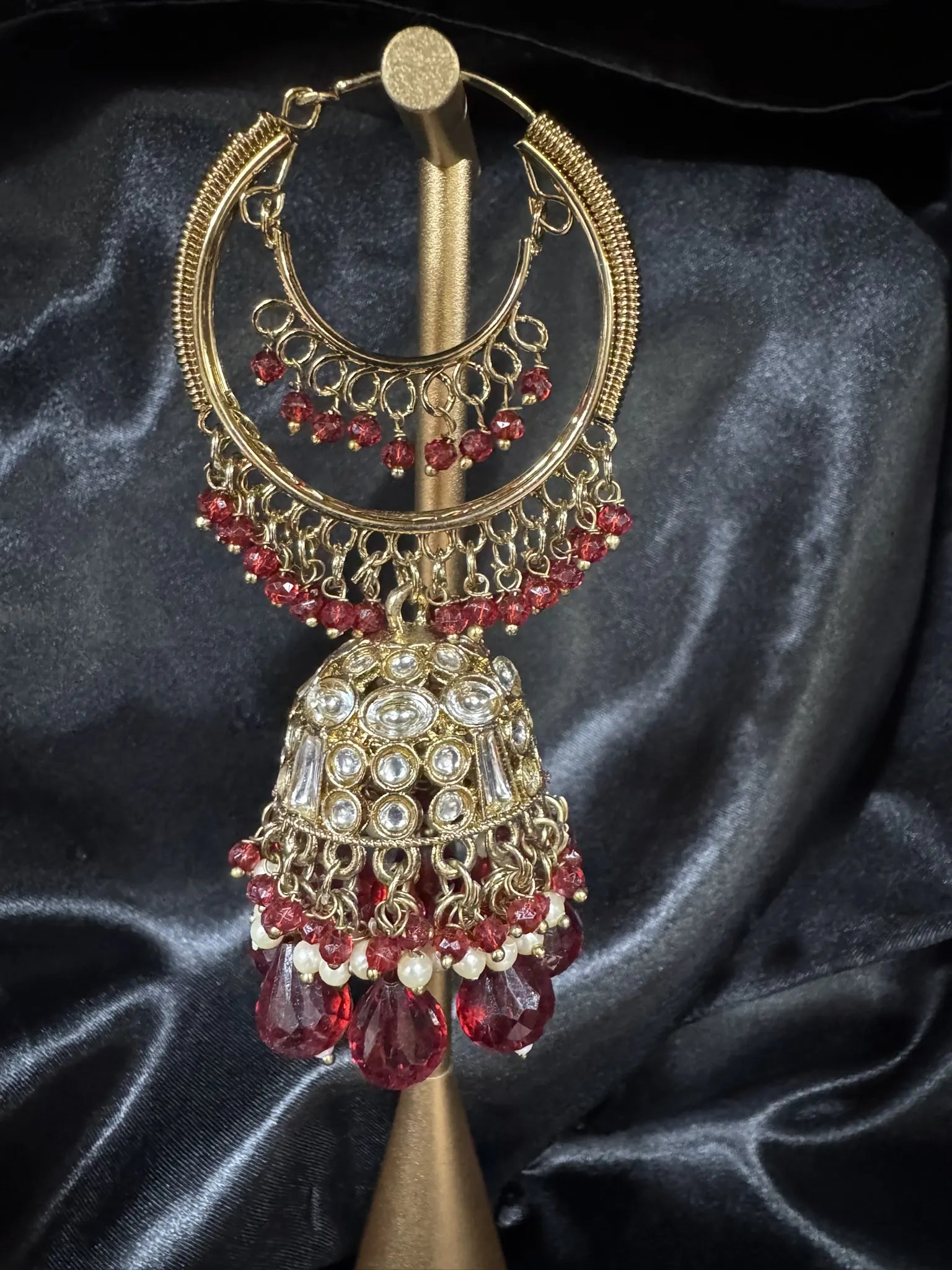 Pakistani design gold and maroon lightweight jhumkay on a stand against a dark background