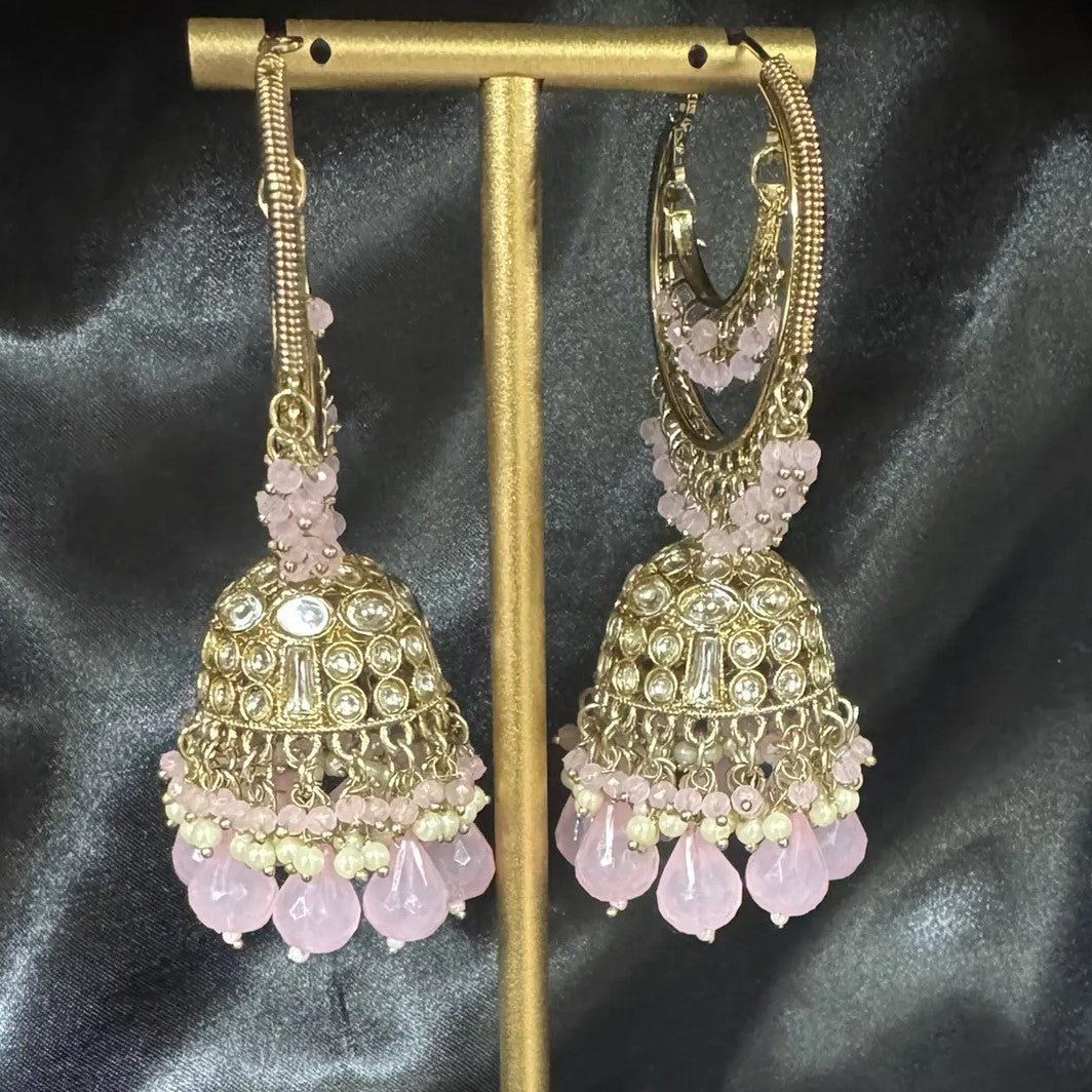 Pakistani design gold and pink lightweight jhumkay on a stand against a dark background