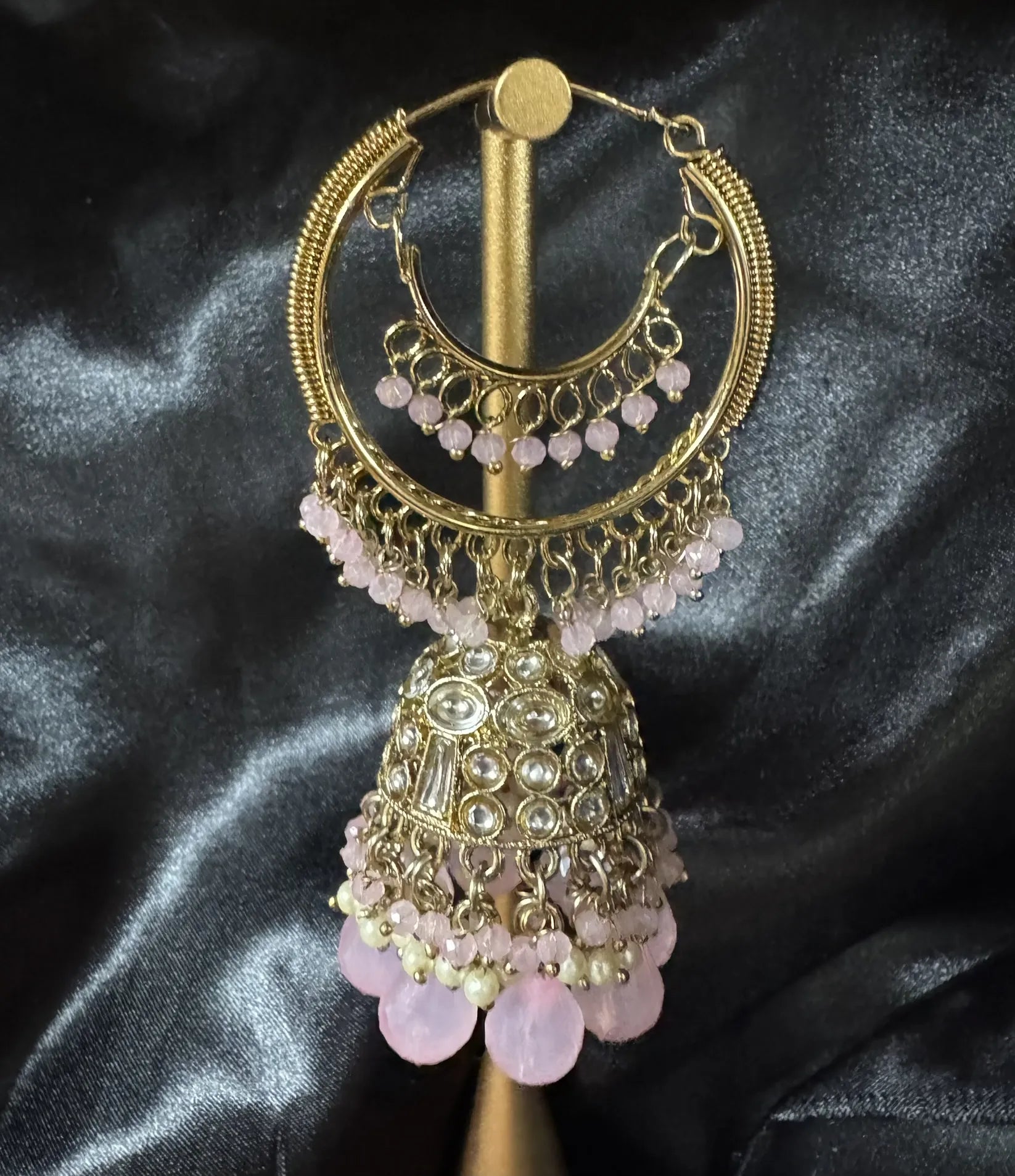 Pakistani design pink and gold lightweight jhumkay on a stand against a dark background