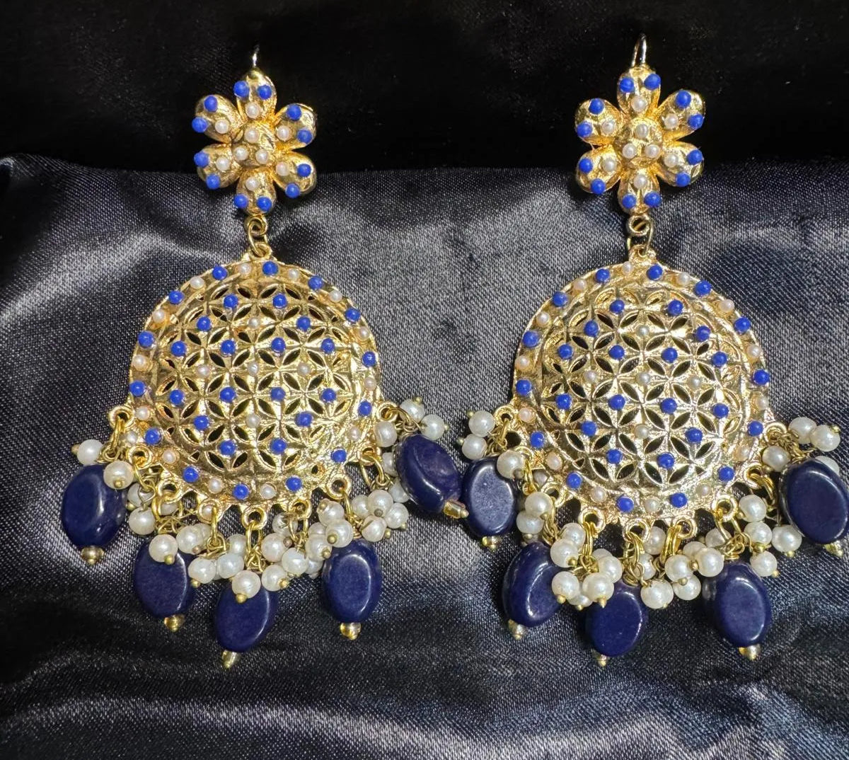 Pair of gold and blue earrings on a dark fabric background