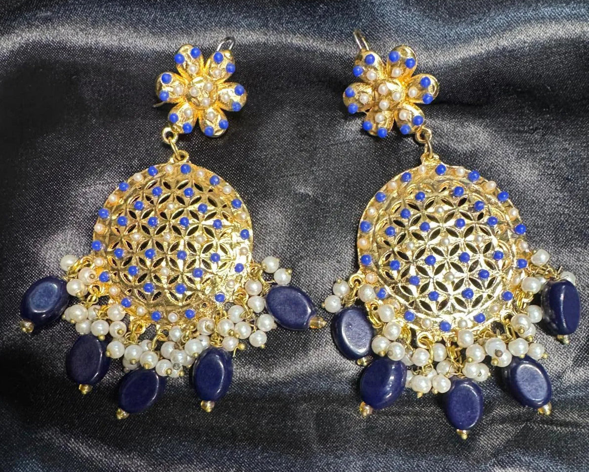 Pair of gold and blue earrings on a dark fabric background
