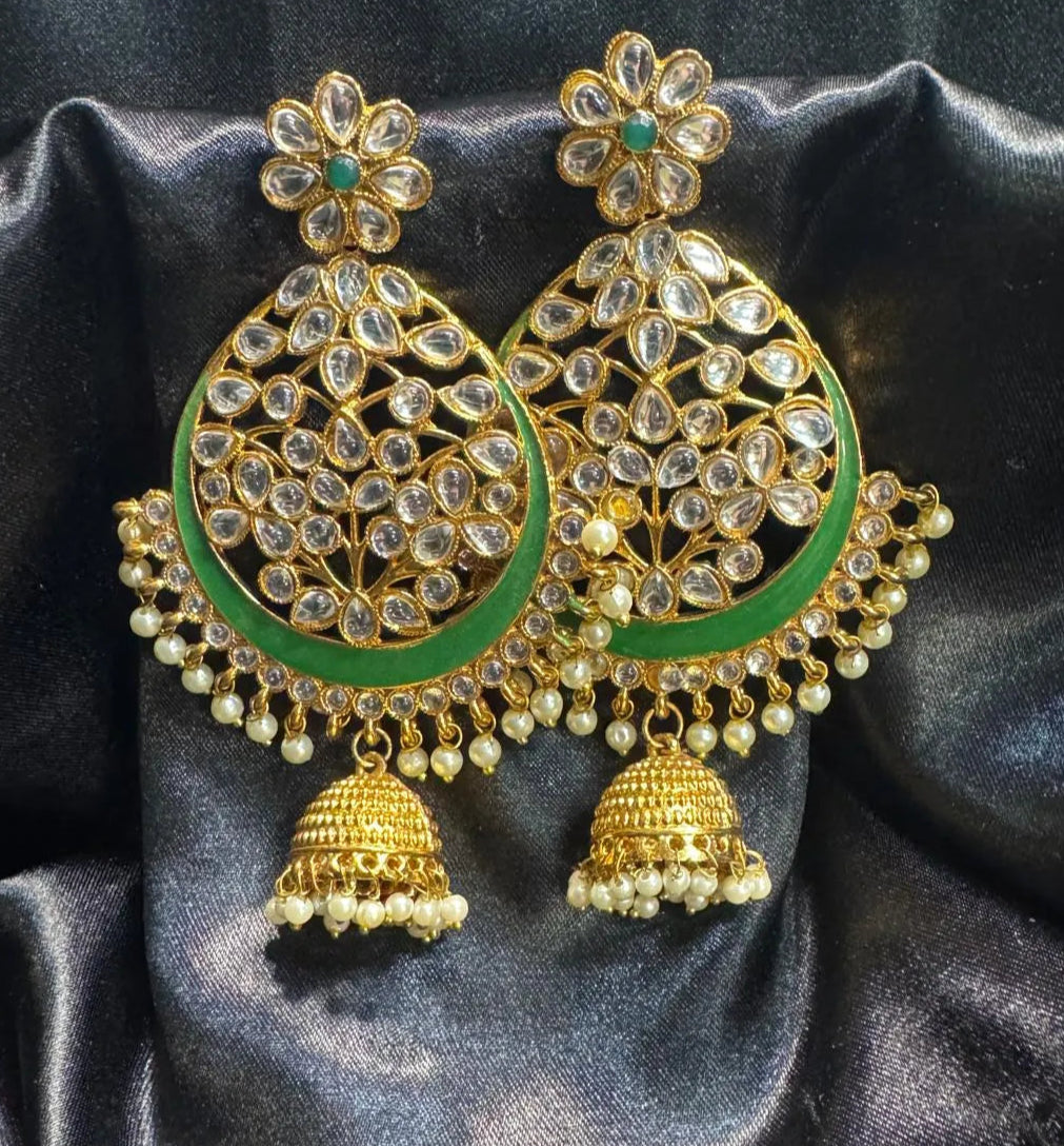 Ornate gold and green earrings on a dark fabric background