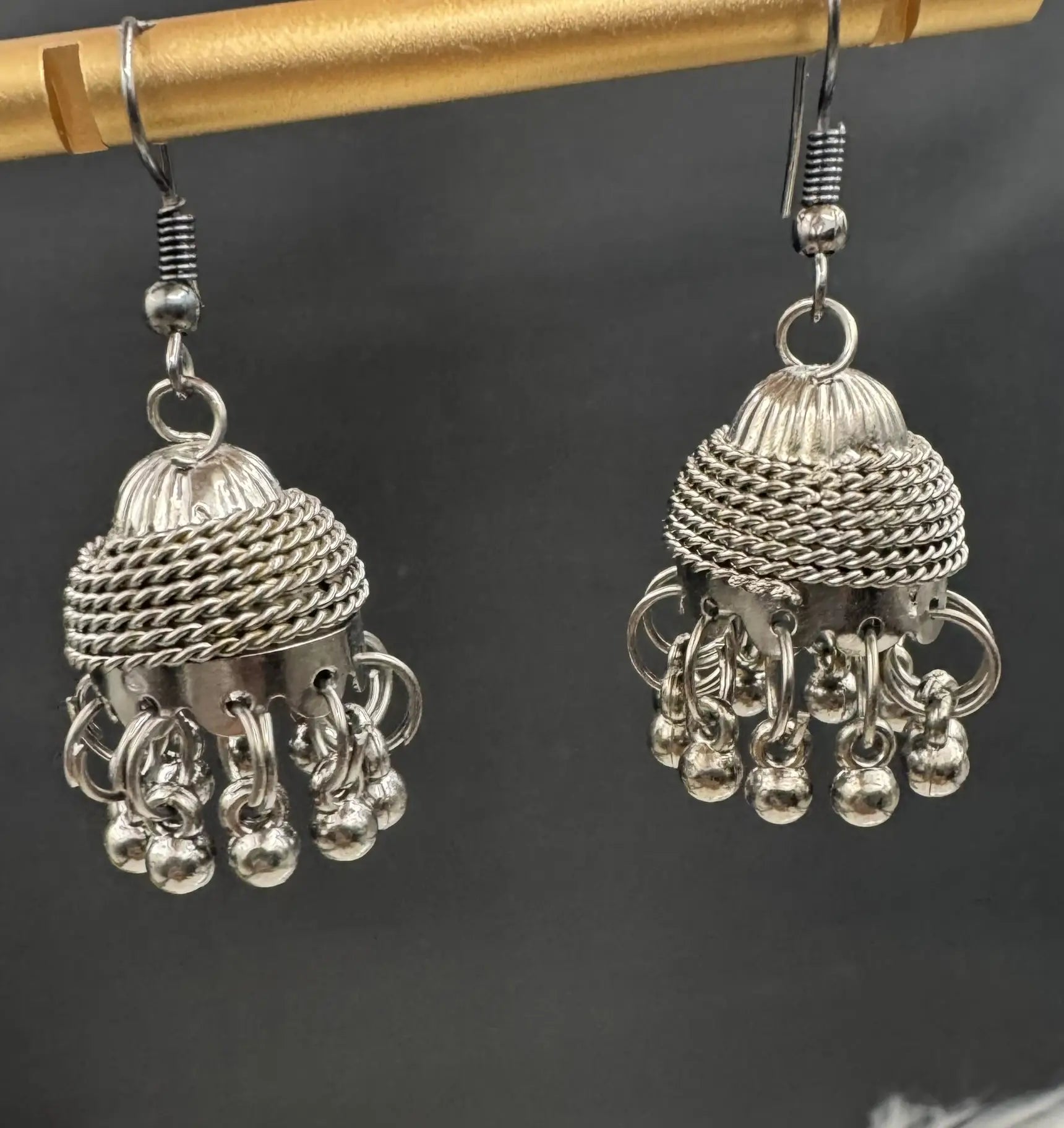 Pair of silver jhumka earrings on a dark background