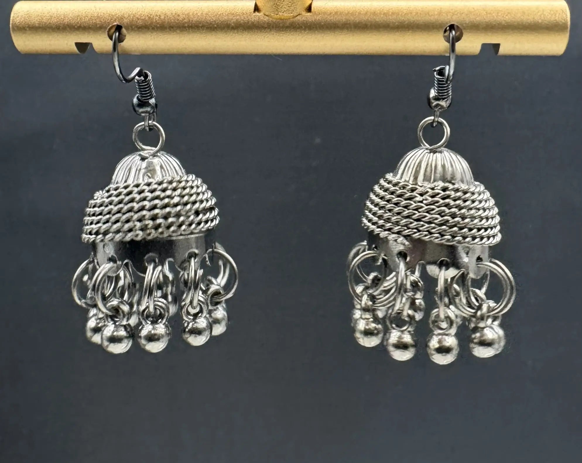 Silver jhumka earrings on a dark background