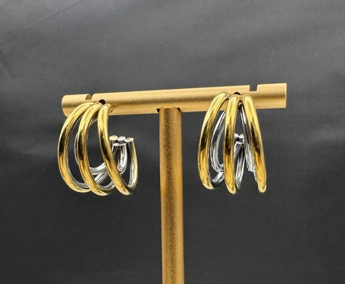 Gold half hoop earrings against a black background. Gold plated and stainless steel
