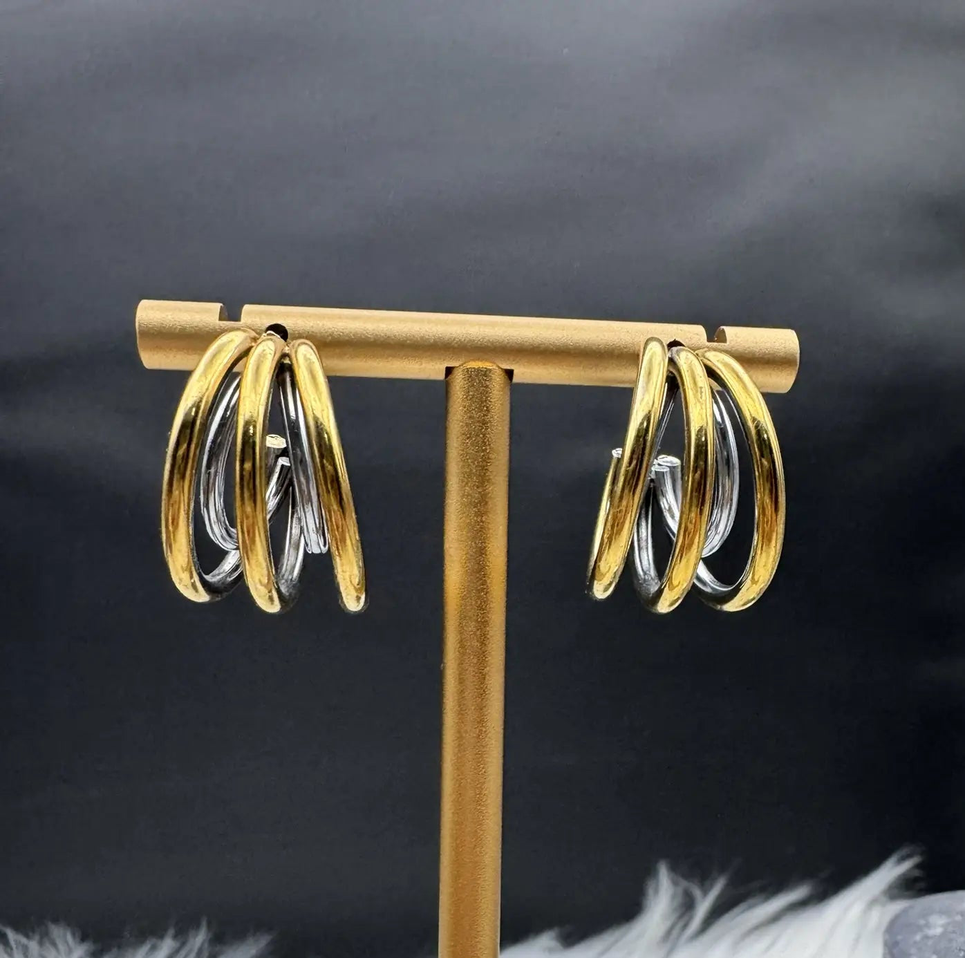 another angle of gold half hoop earrings against a black background. Gold plated and stainless steel