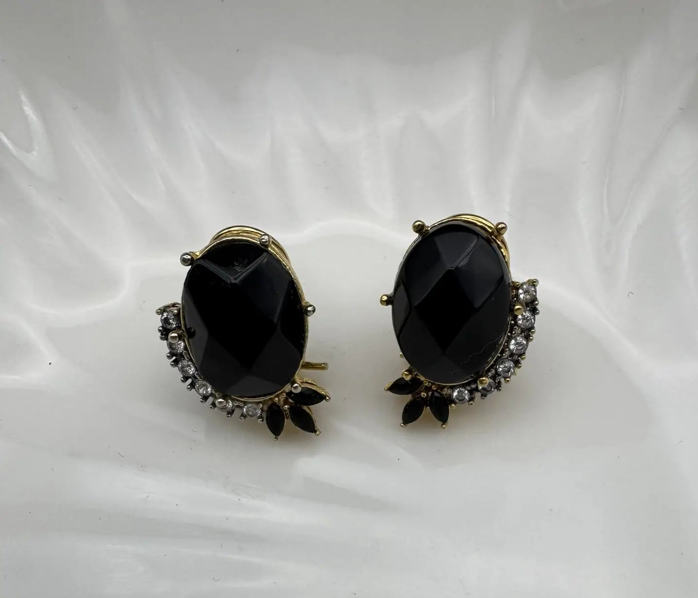Pair of black gemstone earrings with gold accents on a white background