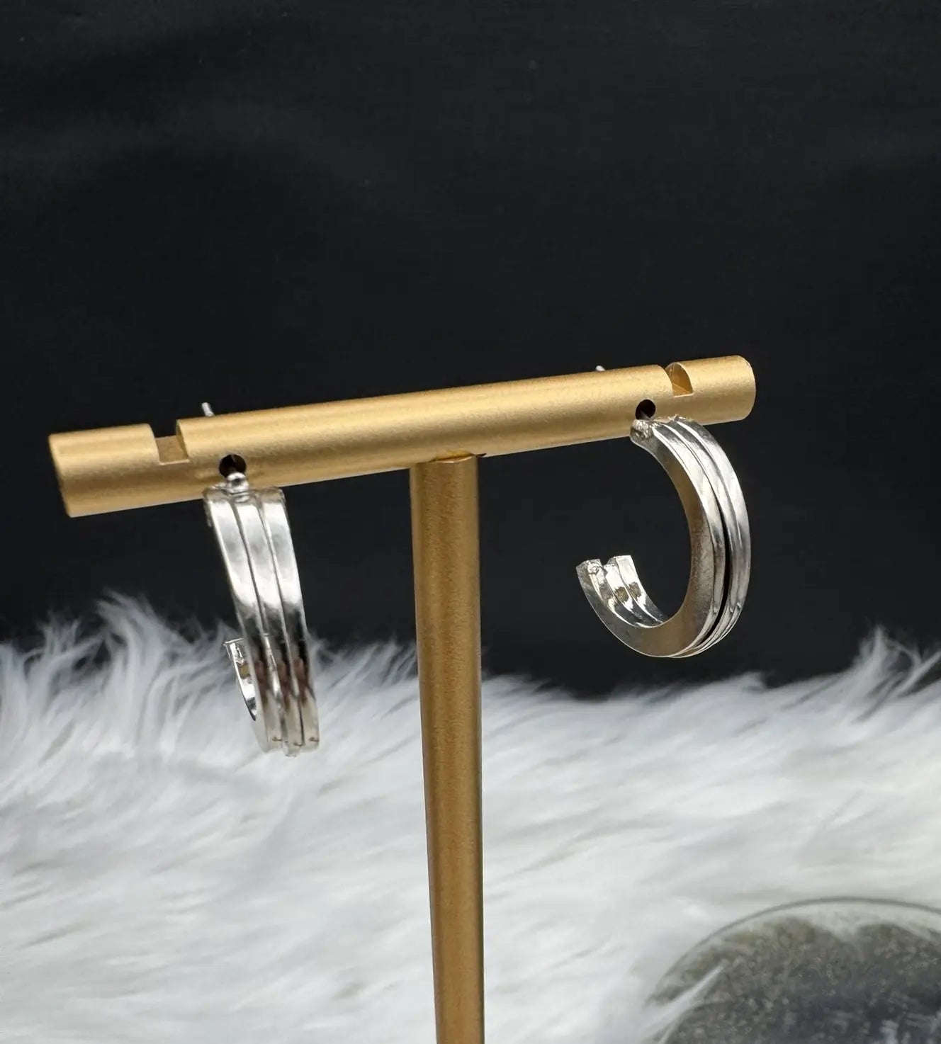 Silver hoop earrings on a white surface with a black background