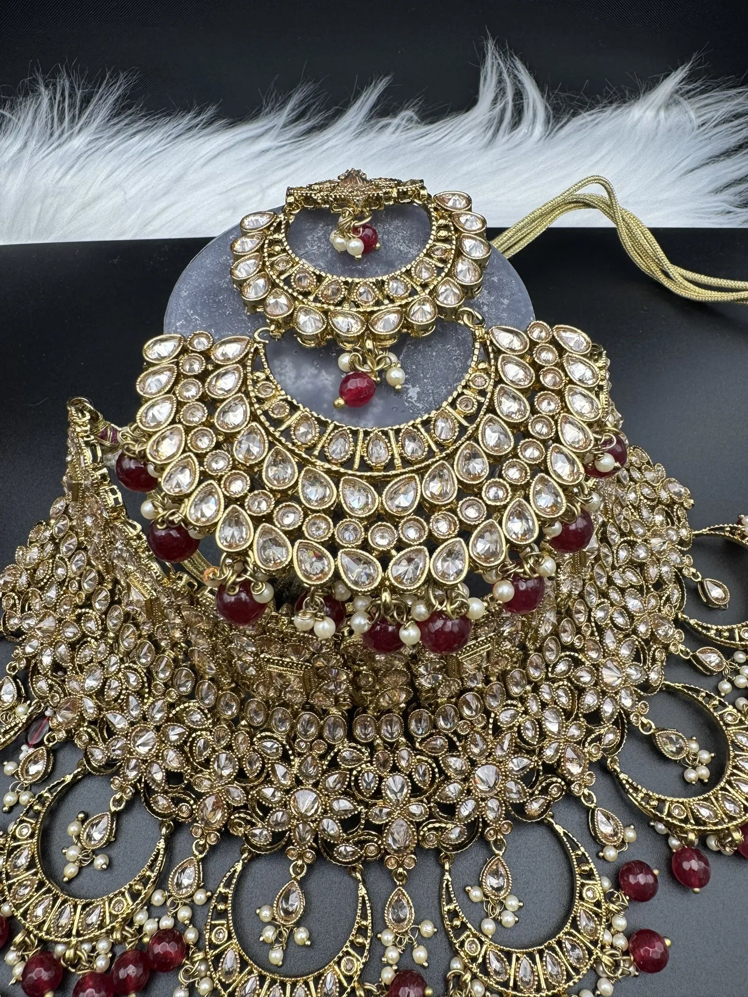 top teeka view of exquisite gold-plated Indian bridal set with red accents, sparkling stones & matching earrings, teeka and a long traditional necklace. Waterproof & anti-tarnish.