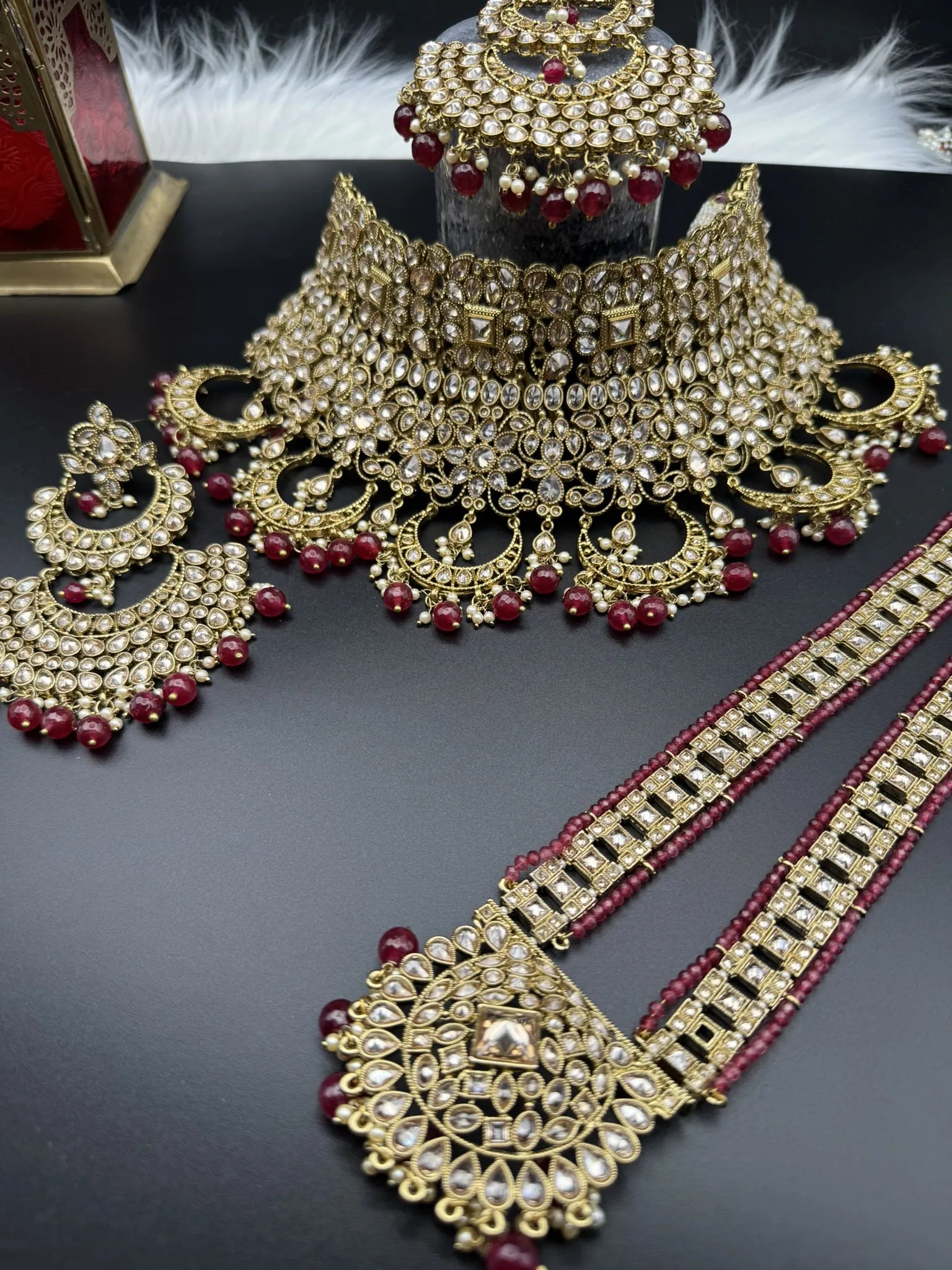 frontal view of exquisite gold-plated Indian bridal set with red accents, sparkling stones & matching earrings, teeka and a long traditional necklace. Waterproof & anti-tarnish.