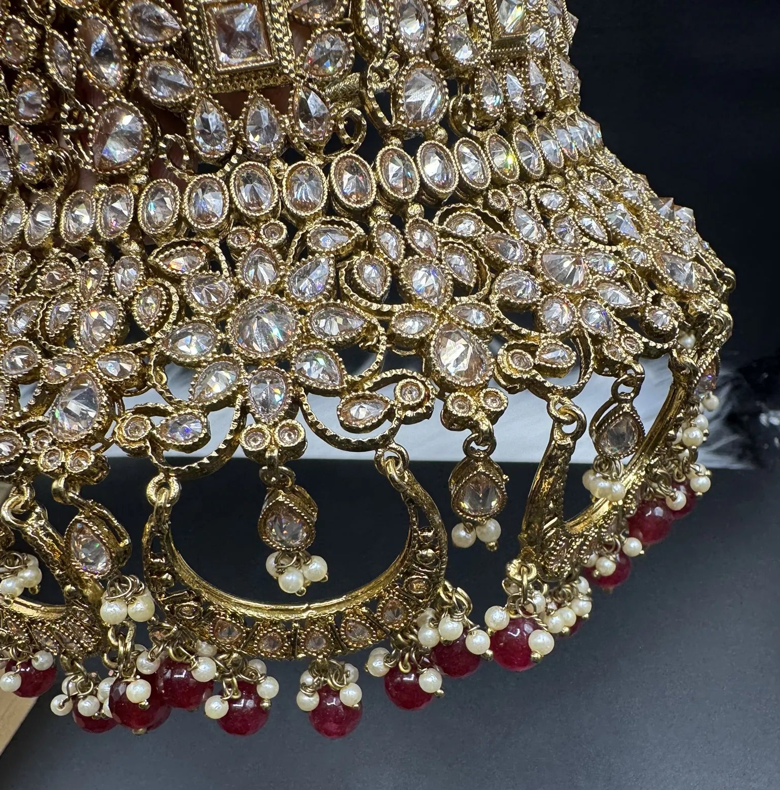 choker focused view exquisite gold-plated Indian bridal set with red accents, sparkling stones & matching earrings, teeka and a long traditional necklace. Waterproof & anti-tarnish.