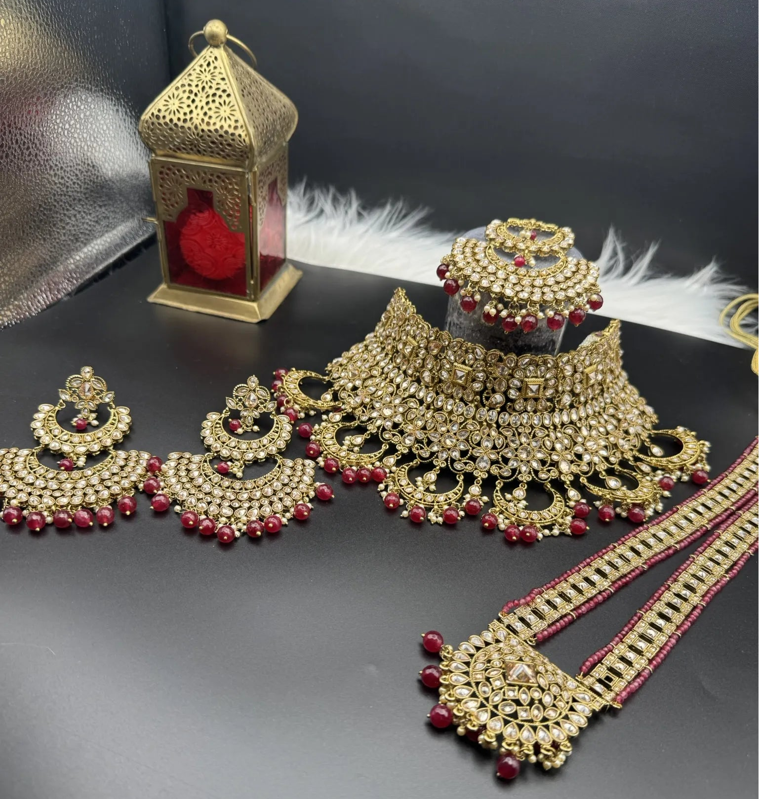 Exquisite gold-plated Indian bridal set with red accents, sparkling stones & matching earrings, teeka and a long traditional necklace. Waterproof & anti-tarnish.